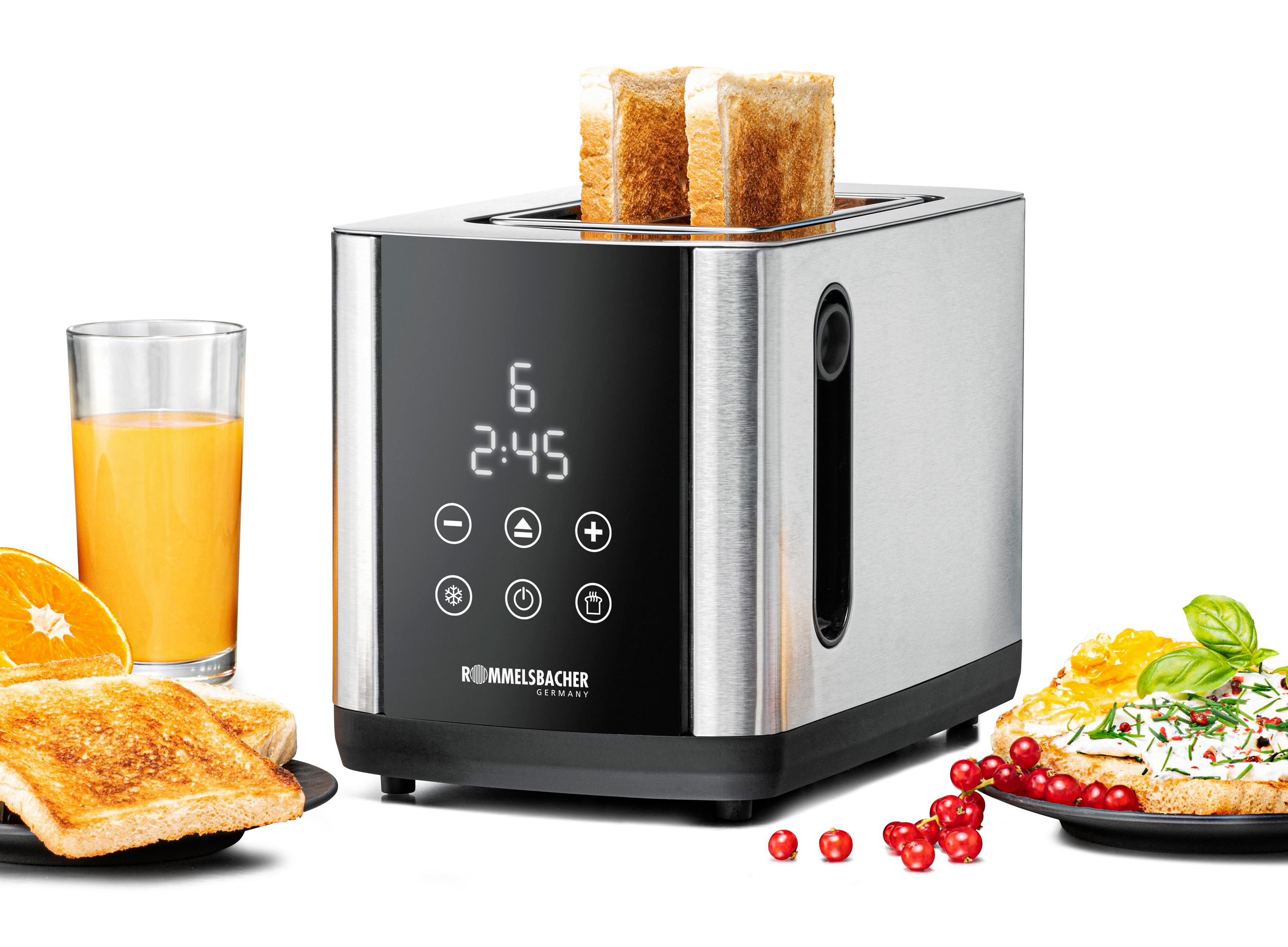 Ein Toaster mit zwei Toastscheiben. Orangensaft, Toast mit Marmelade und rote Beeren sind daneben.