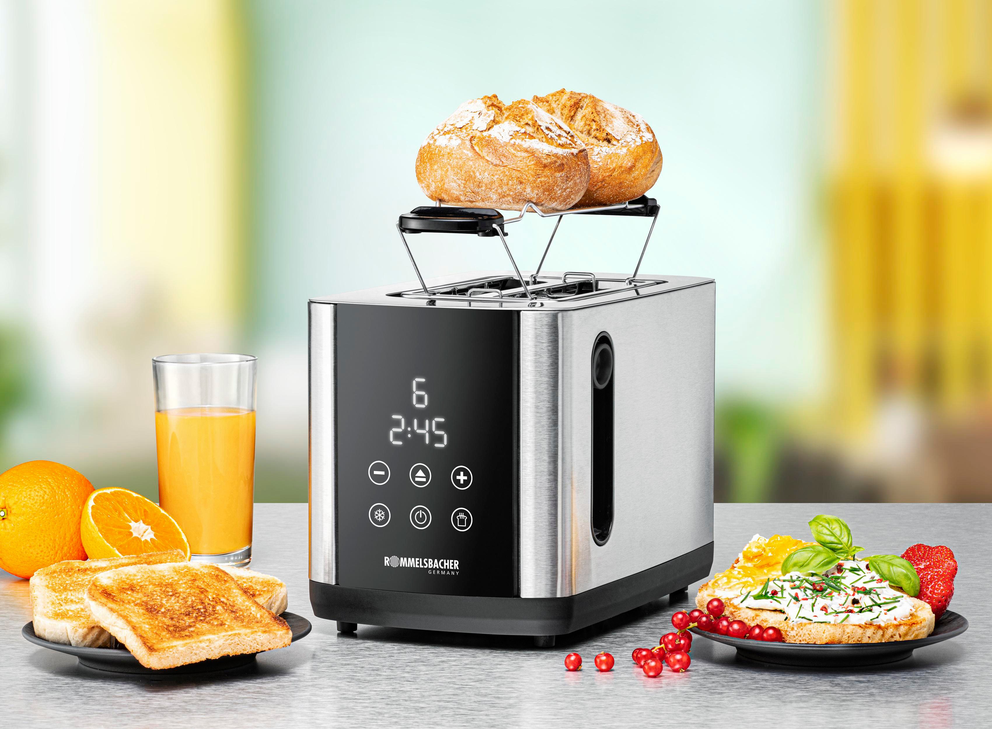 Toaster mit Brot, Orangensaft und Belägen auf einem Teller. Die Zeit ist 2:45.