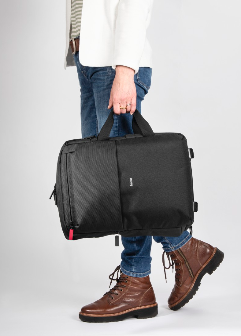 Personne en jean et bottes portant une mallette noire.