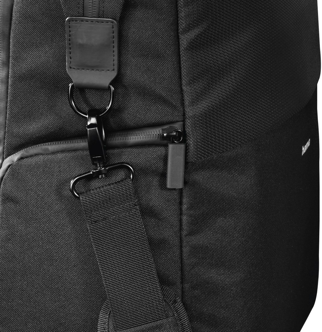Gros plan sur un sac noir avec une sangle et un fermoir en métal attaché, fermeture éclair visible.