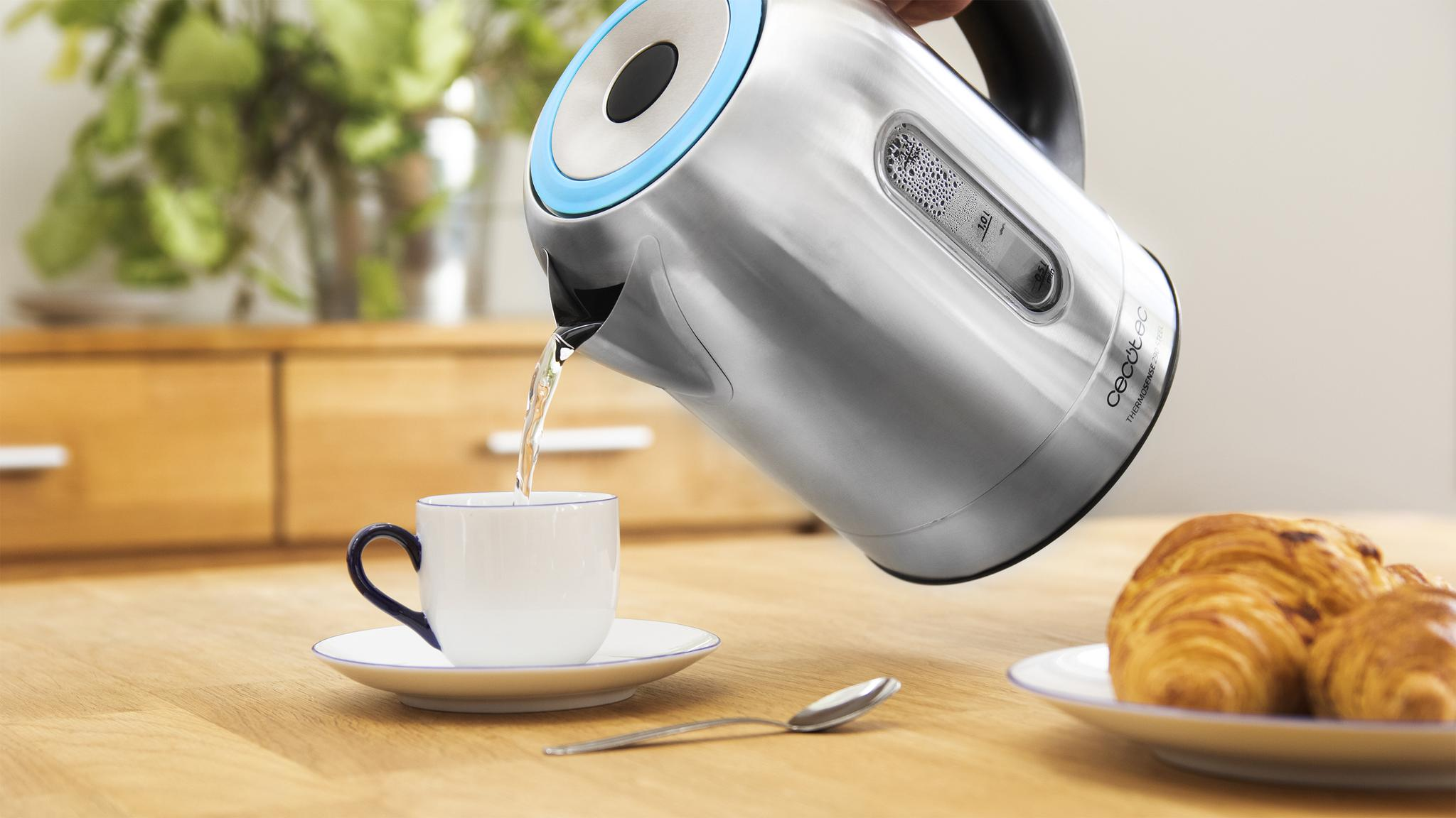 Una tetera plateada vierte agua en una taza blanca.