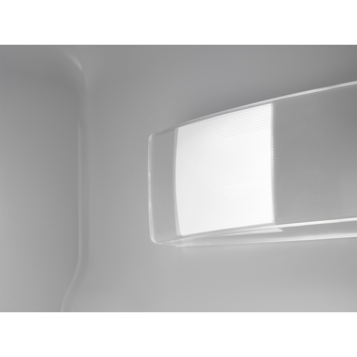 Interno del frigorifero con luce intensa e ripiano in vetro. Tonalità bianche e grigie.