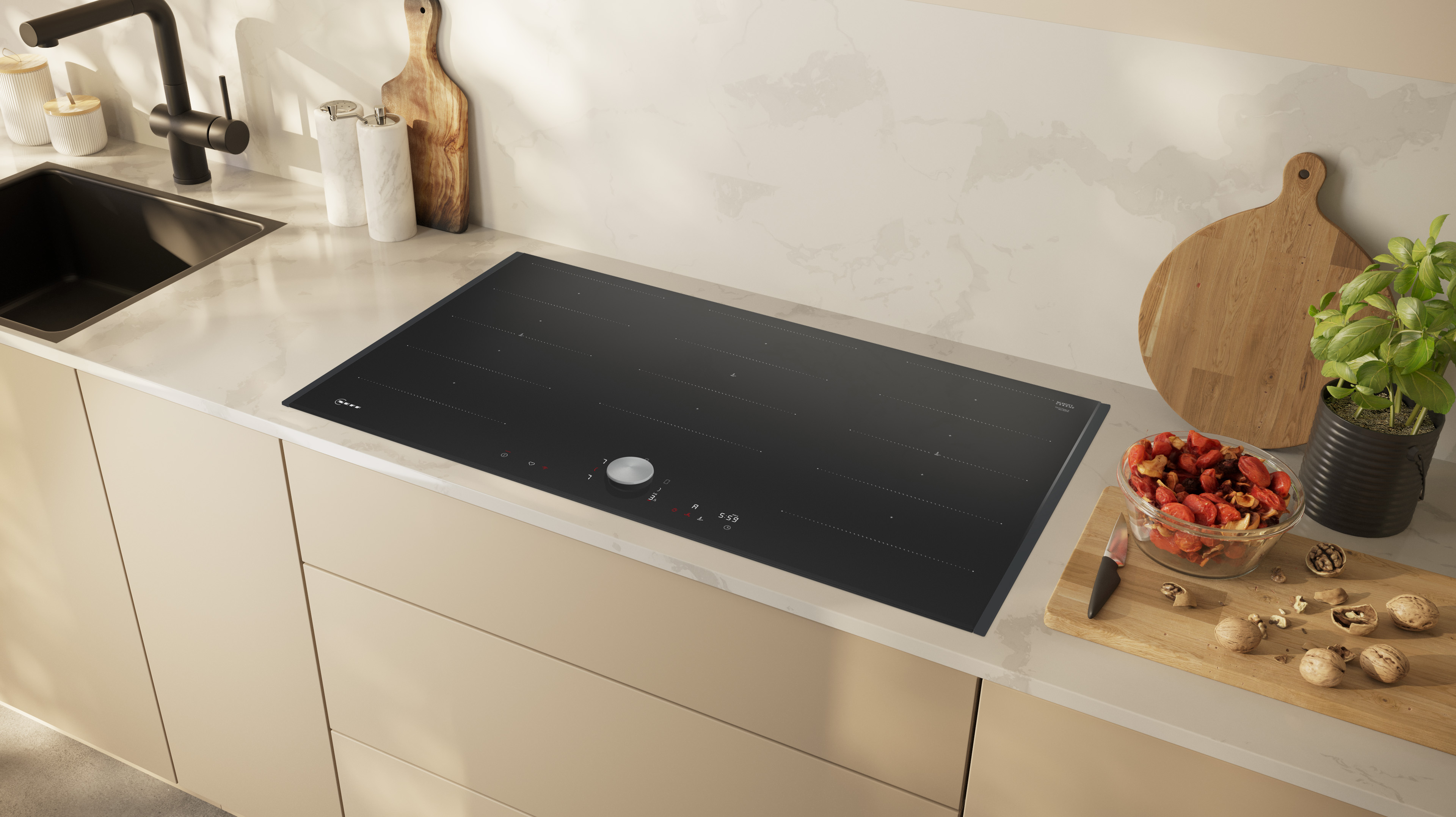 Schwarzes Induktionskochfeld auf einer Arbeitsplatte. Hintergrund hat ein Waschbecken, Schneidebretter und Küchenartikel.