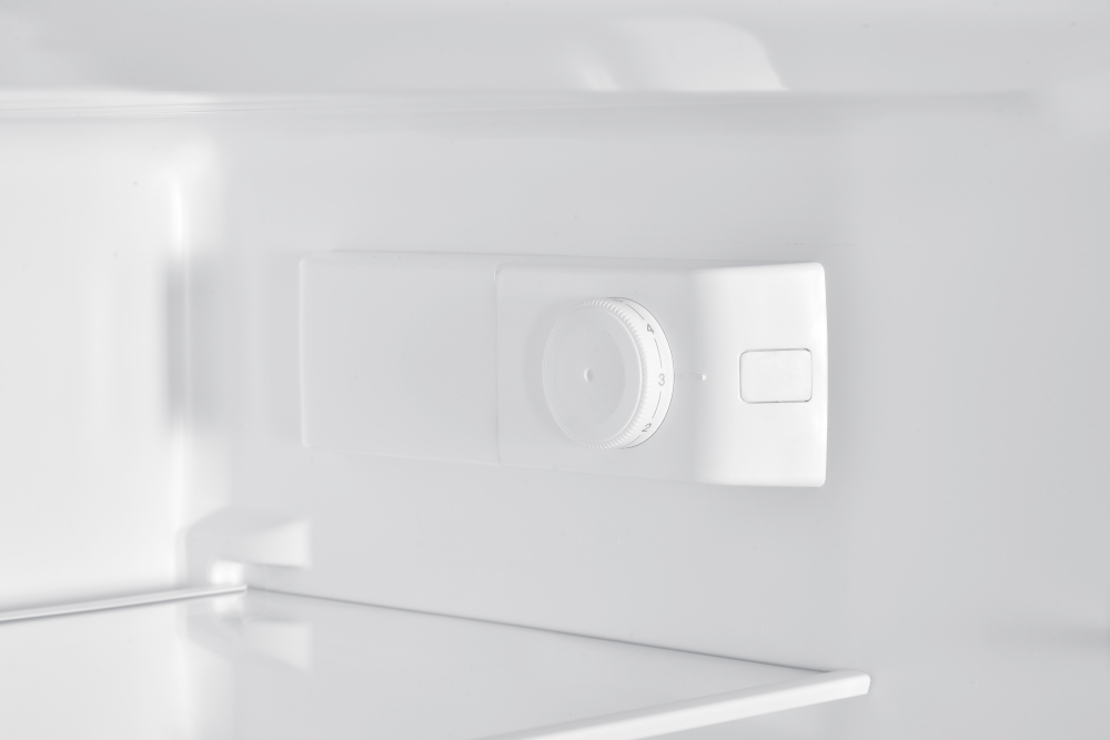 Inside of a white refrigerator showing the temperature control dial.