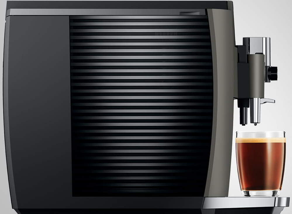 Macchina per espresso che eroga caffè in un bicchiere, vista laterale, design grigio e nero.