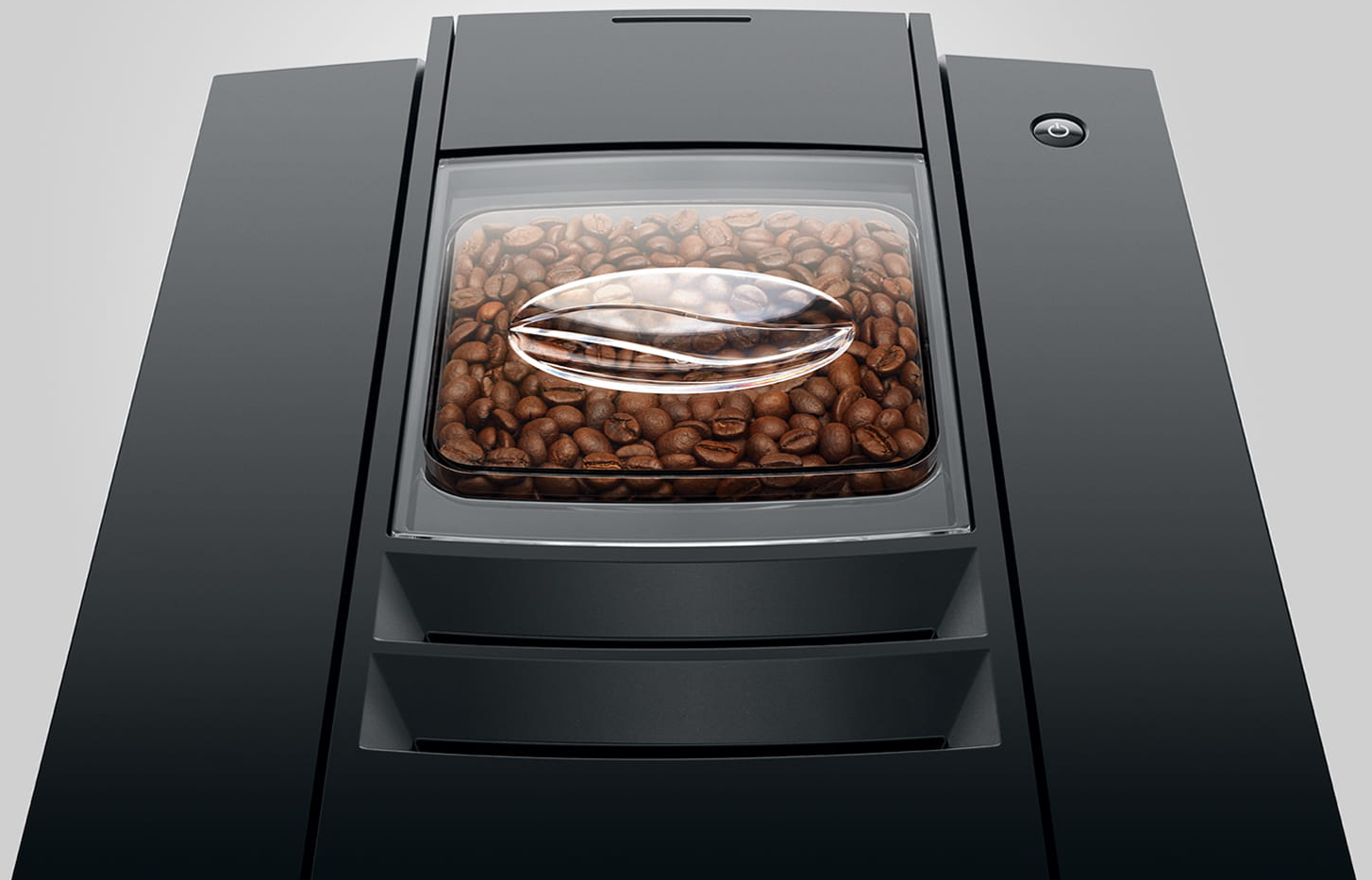 Macchina da caffè nera con un contenitore di fagioli pieno di fagioli marroni, vista dall'alto.
