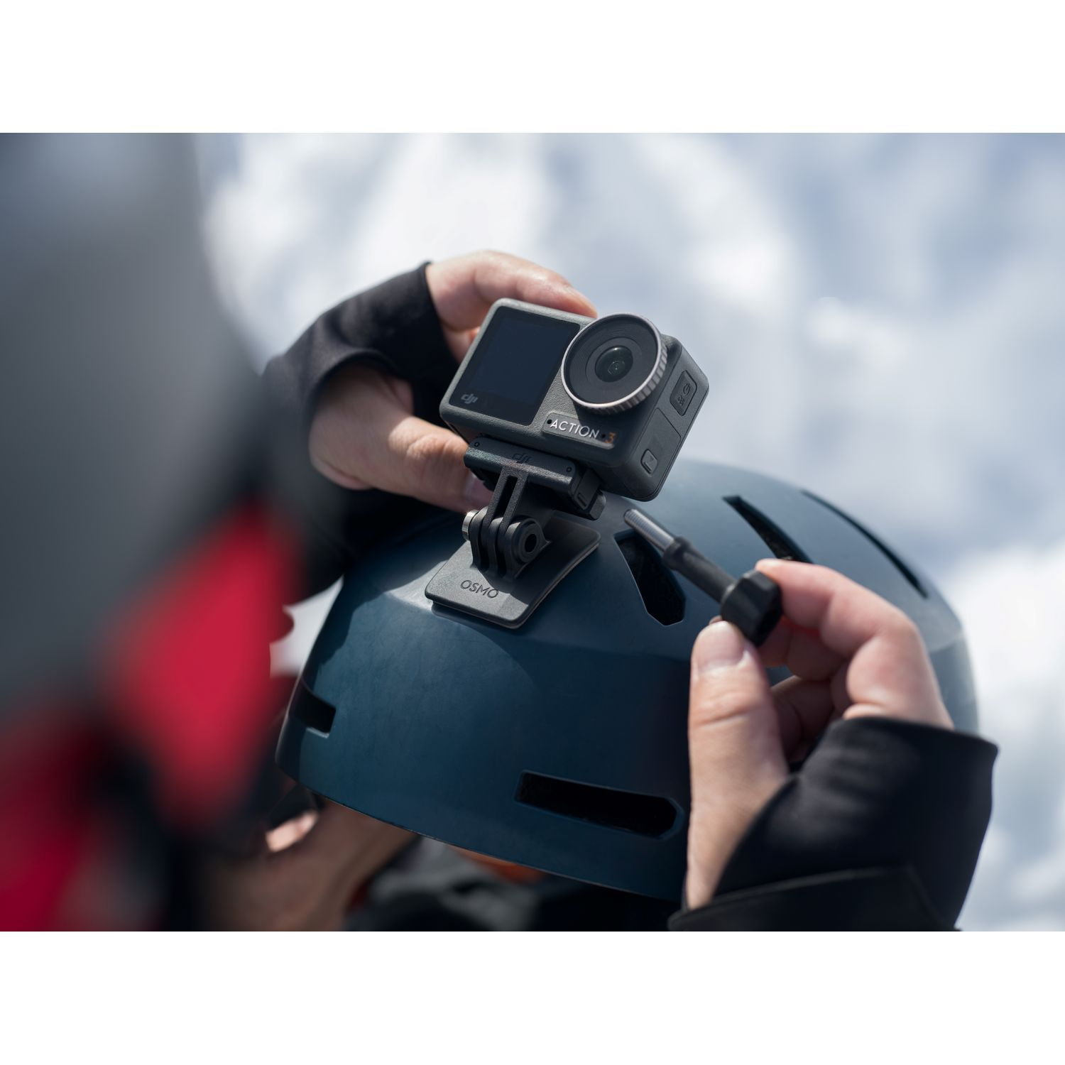 Personne fixant une caméra d'action sur un casque. Ciel et nuages en arrière-plan.