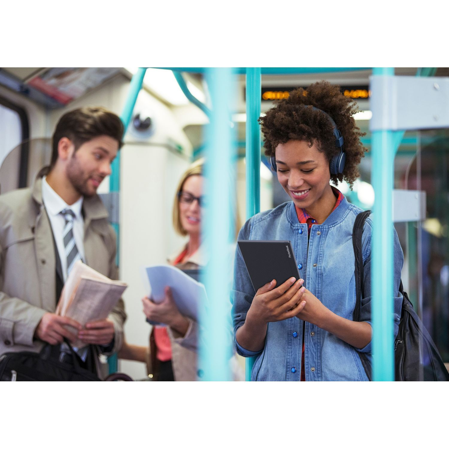 Femme dans un train lisant une tablette, personnes autour.