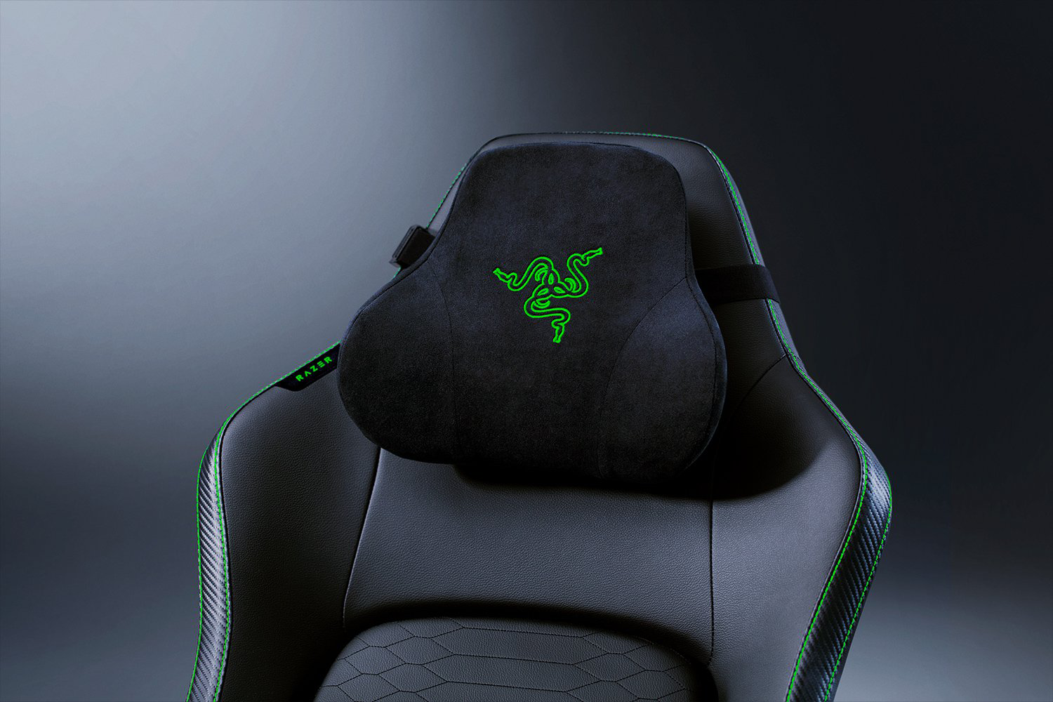 Fekete Razer gamer szék fejtámlája zöld díszítéssel és logóval. Szürke háttér előtt.