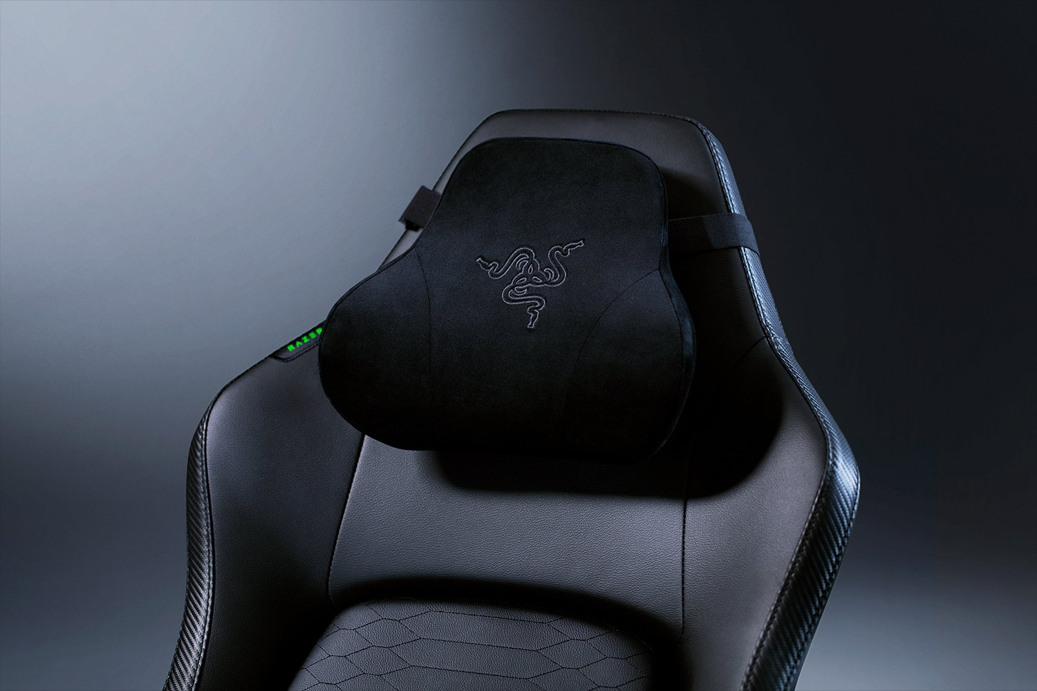 Fekete gamer szék fekete fejtámlával, Razer logóval és zöld részletekkel.
