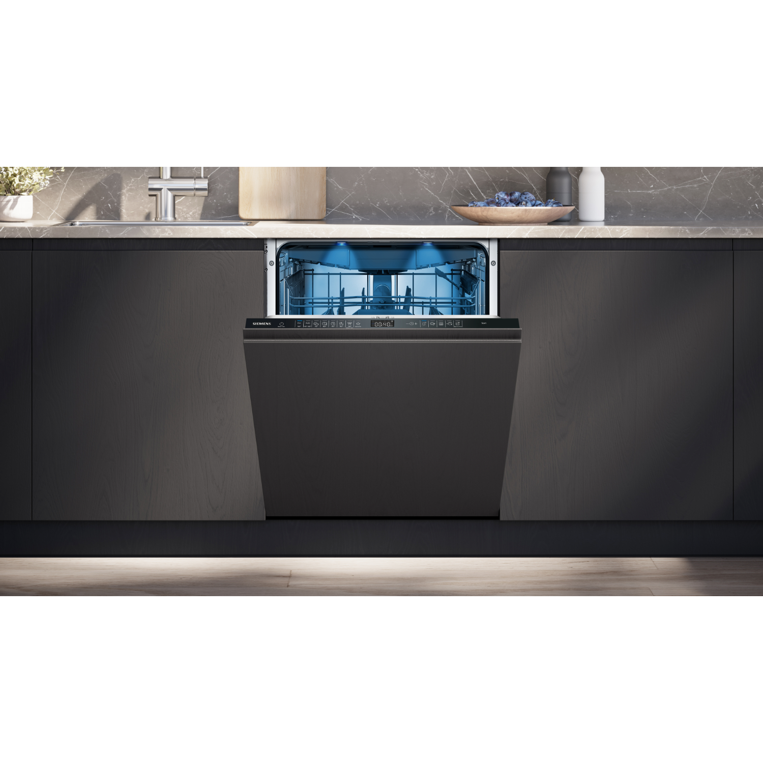 A modern, open dishwasher with blue interior light, inside a dark kitchen setting.