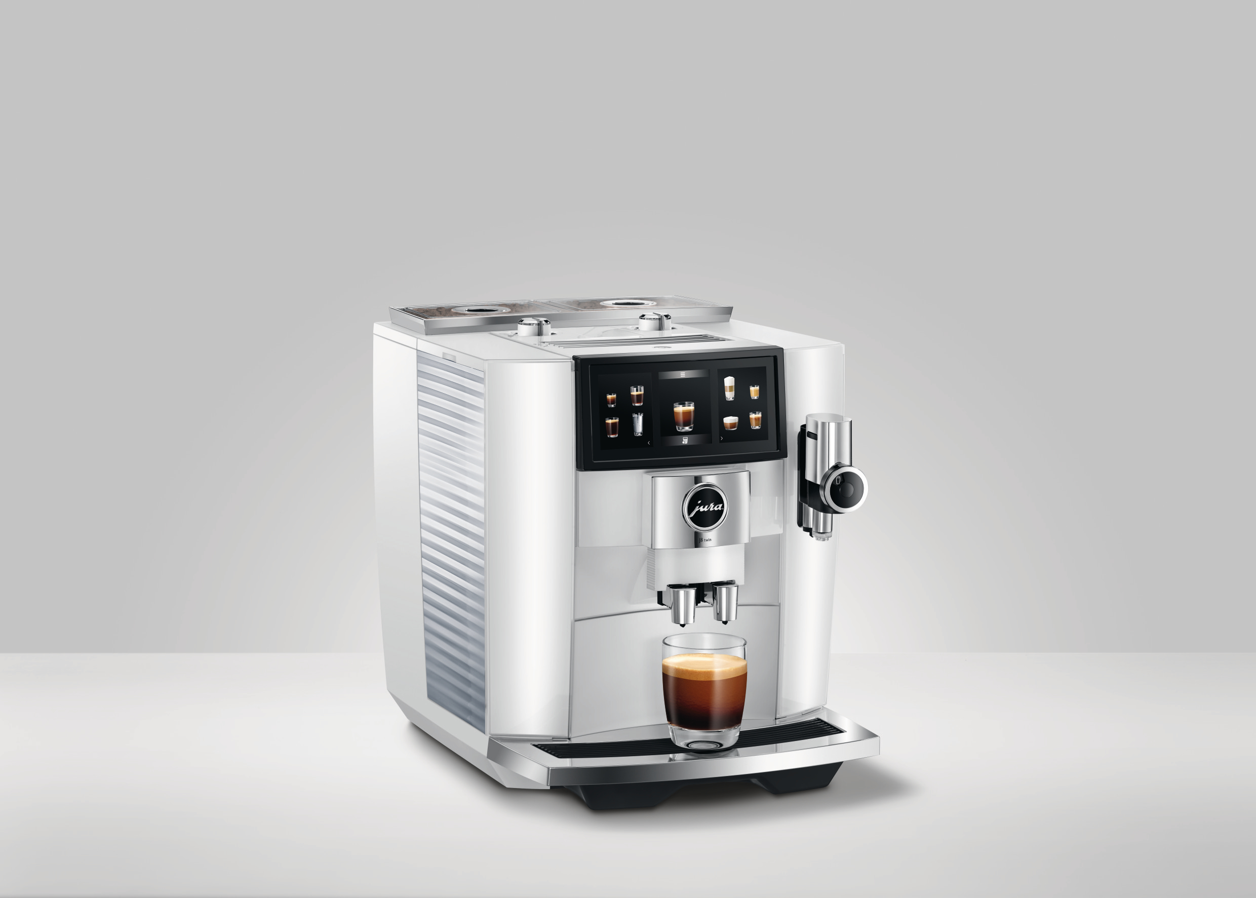 Eine weiße Jura-Kaffeemaschine mit einer Tasse Kaffee. Auf weißer Oberfläche, vor grauem Hintergrund.