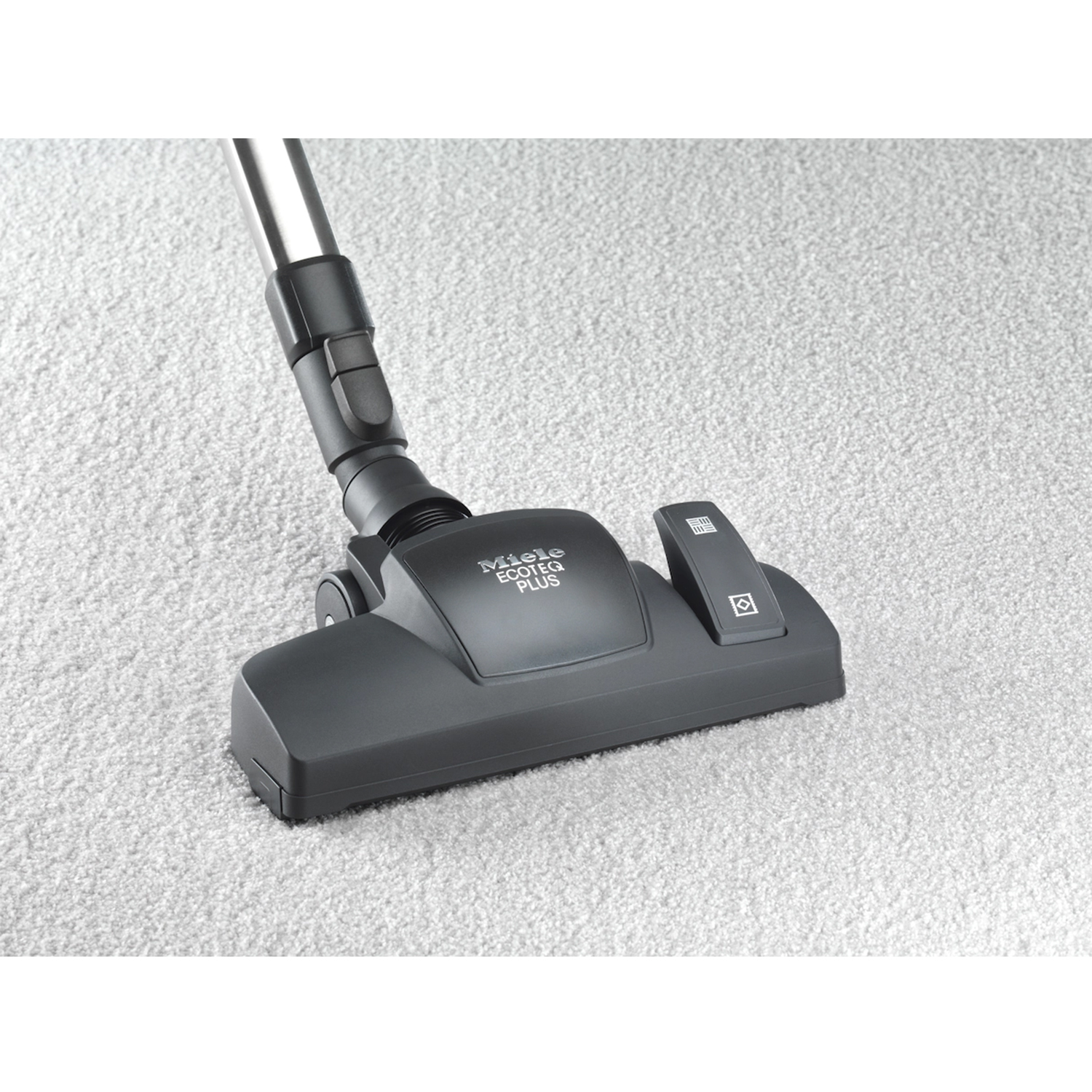 Testa di aspirapolvere su tappeto, con logo Miele visibile. Grigio e nero.
