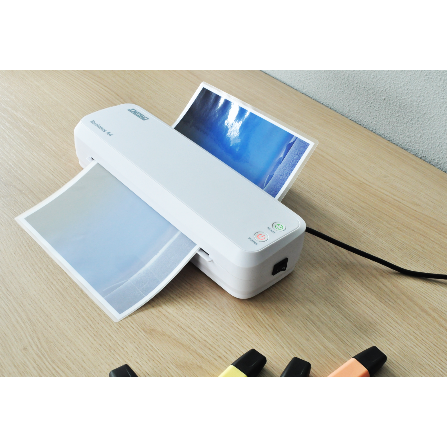 White laminator with paper, a power button, and green and red light buttons on a table.