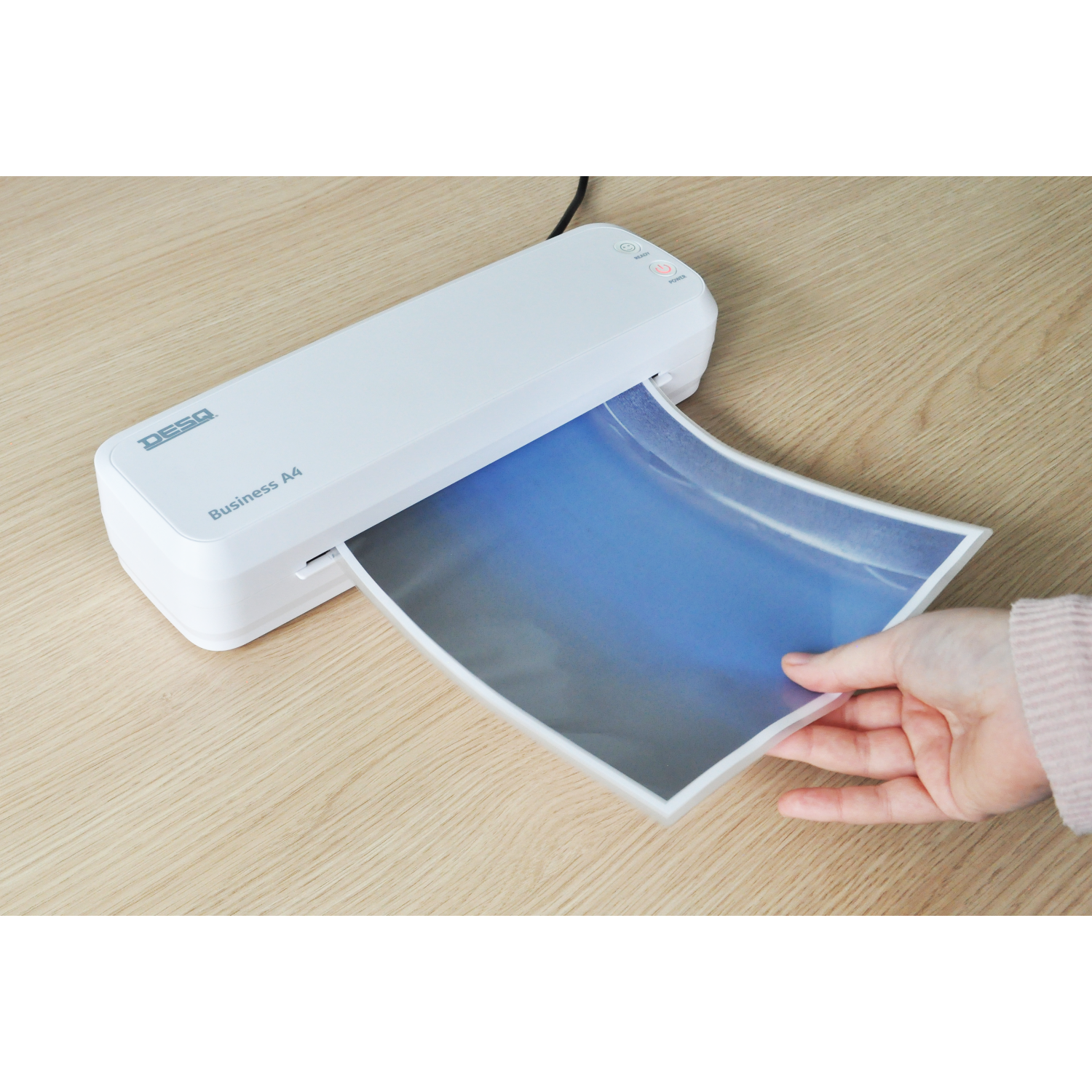 A white laminator with a hand inserting a blue-sky image.