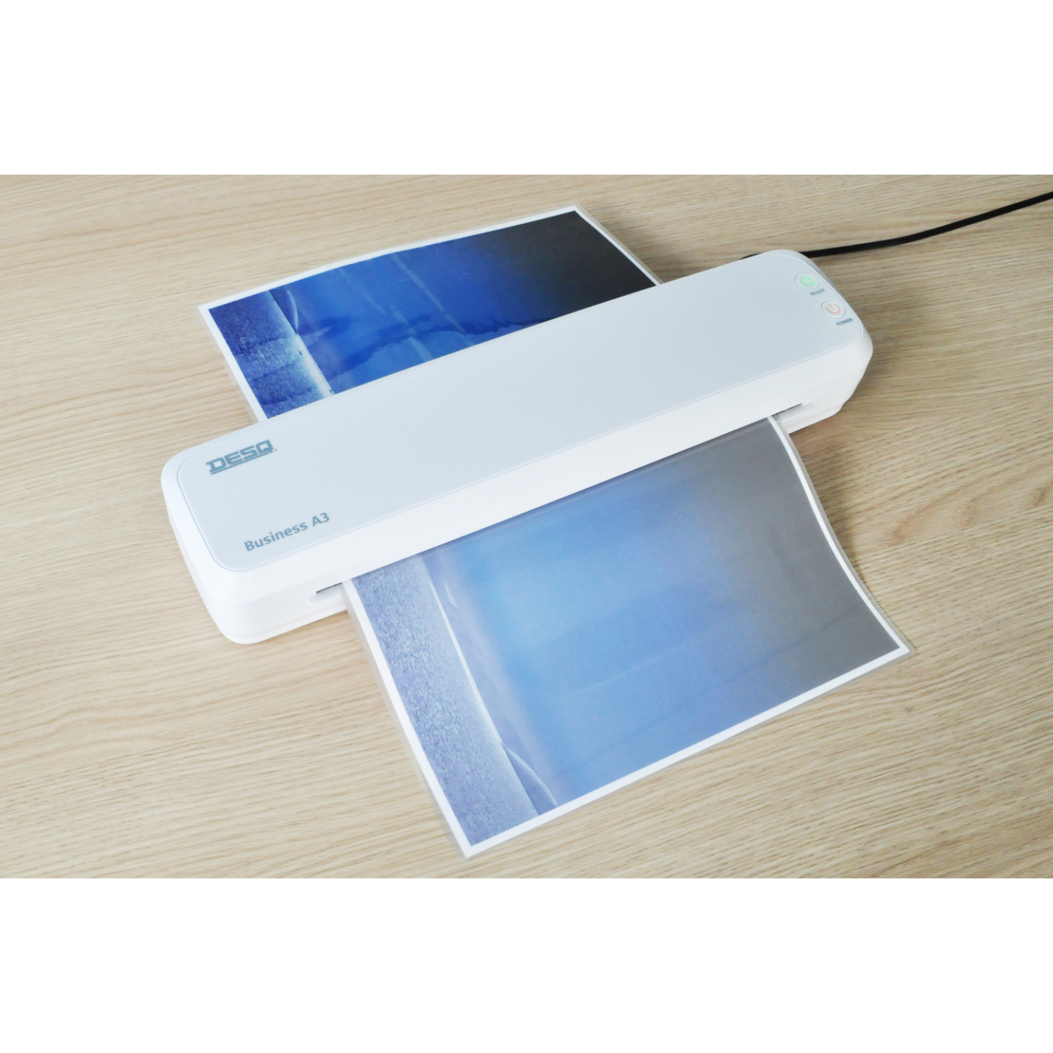 A white laminator with paper being fed through. A blue and white image is visible.