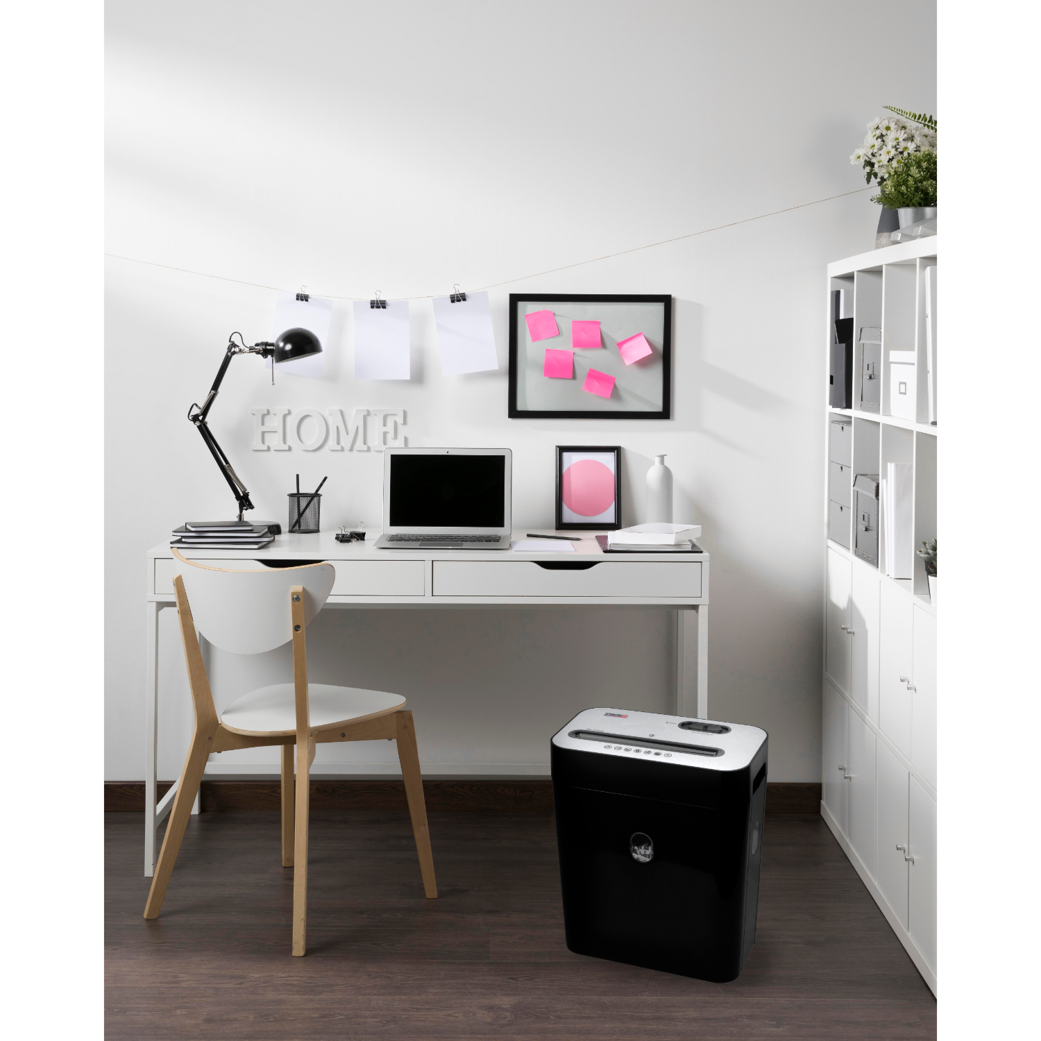 A white desk with a laptop, lamp, and shredder, with a home sign.