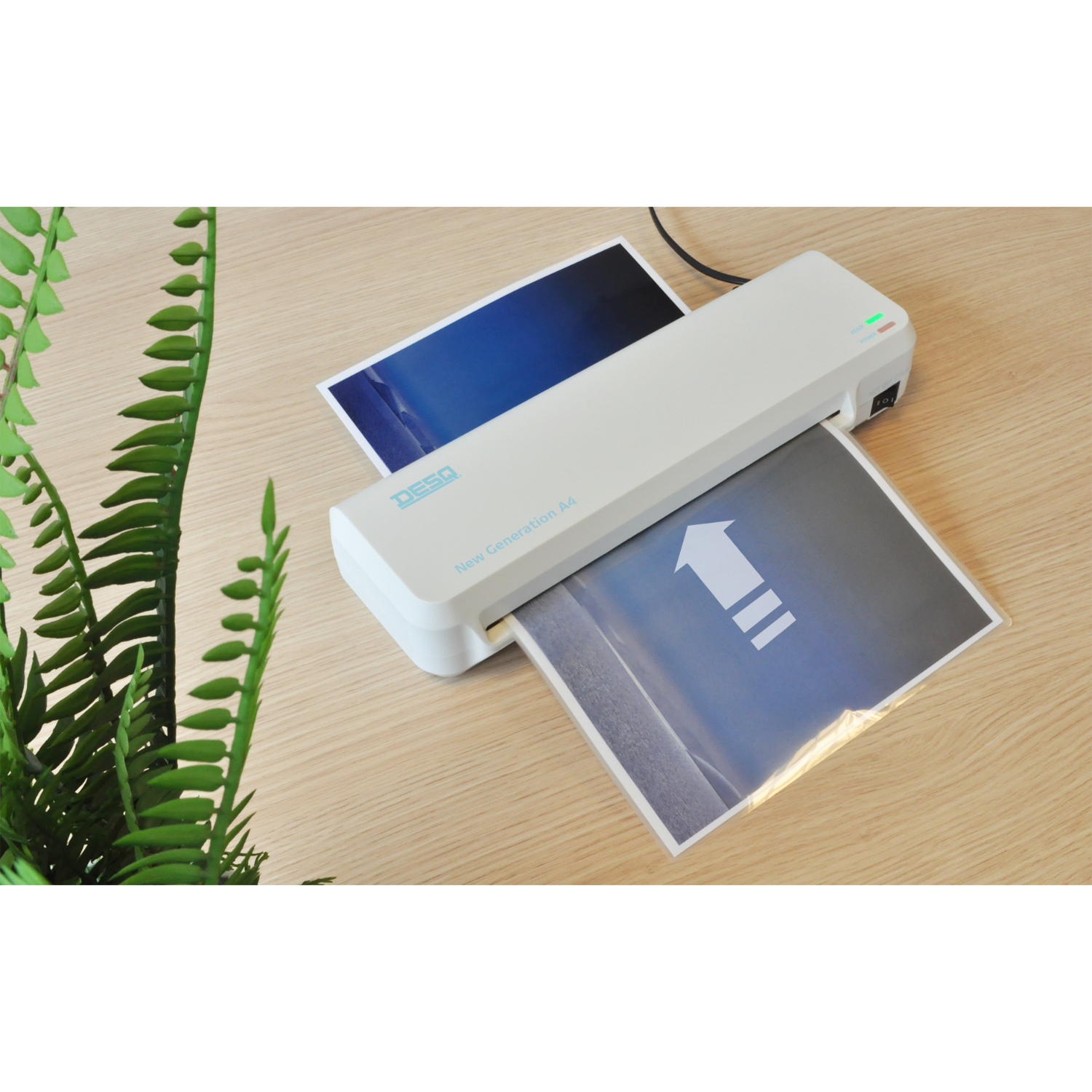 A white laminator with a paper inside. A plant is on the left side.