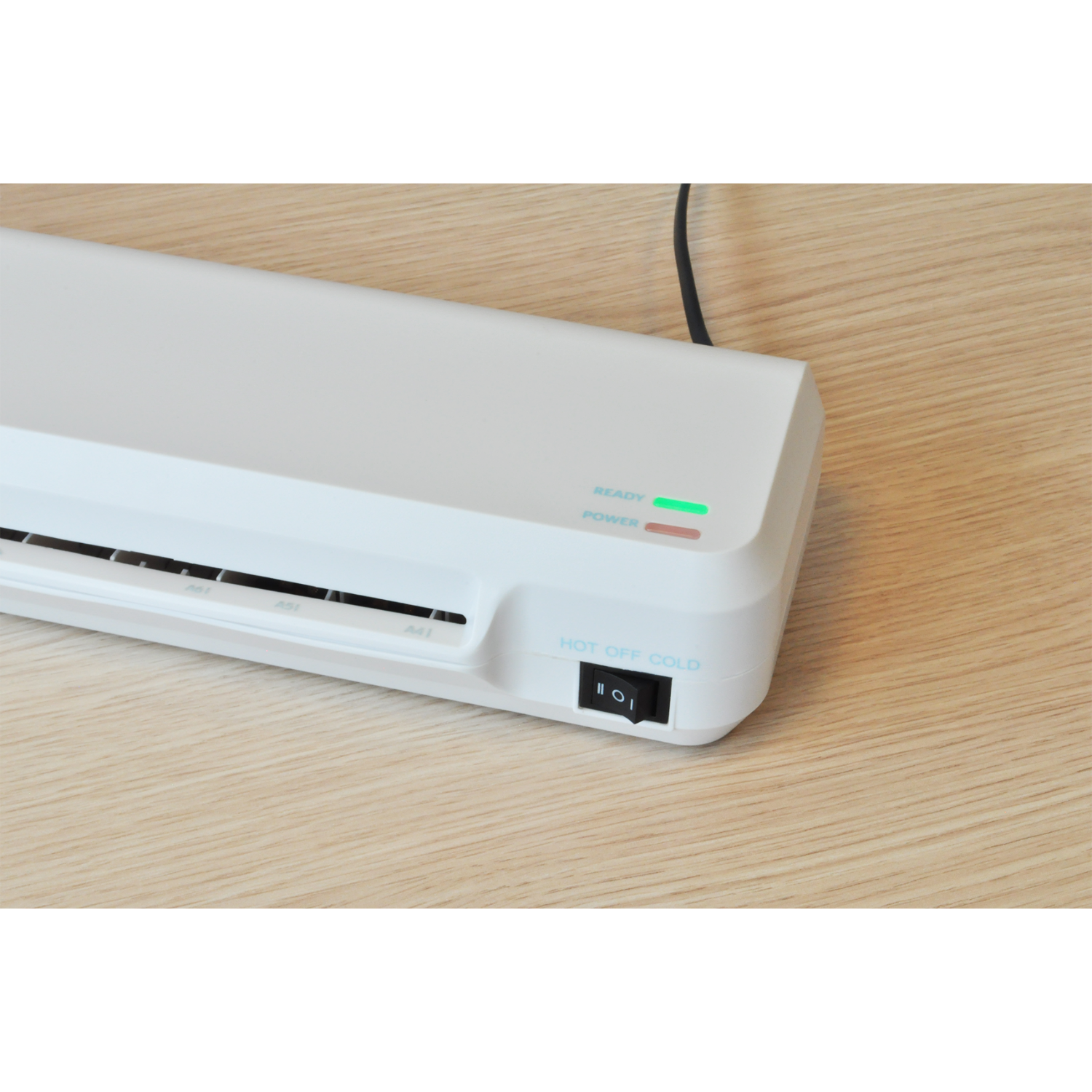 White laminator with power and ready lights illuminated, on a wooden surface, and a power switch.