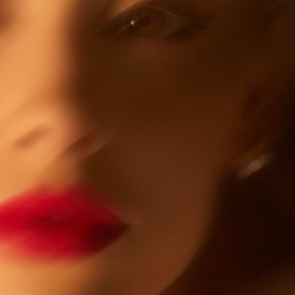 Nahaufnahme eines Frauen-Gesichts. Roter Lippenstift und ein sichtbares Auge.