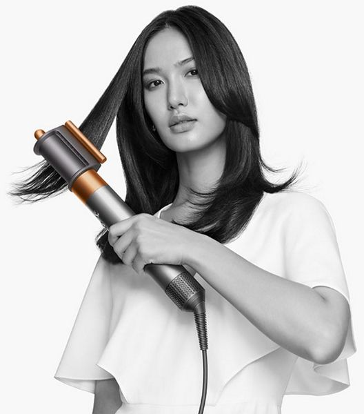 Una donna che si acconcia i capelli con uno styler.