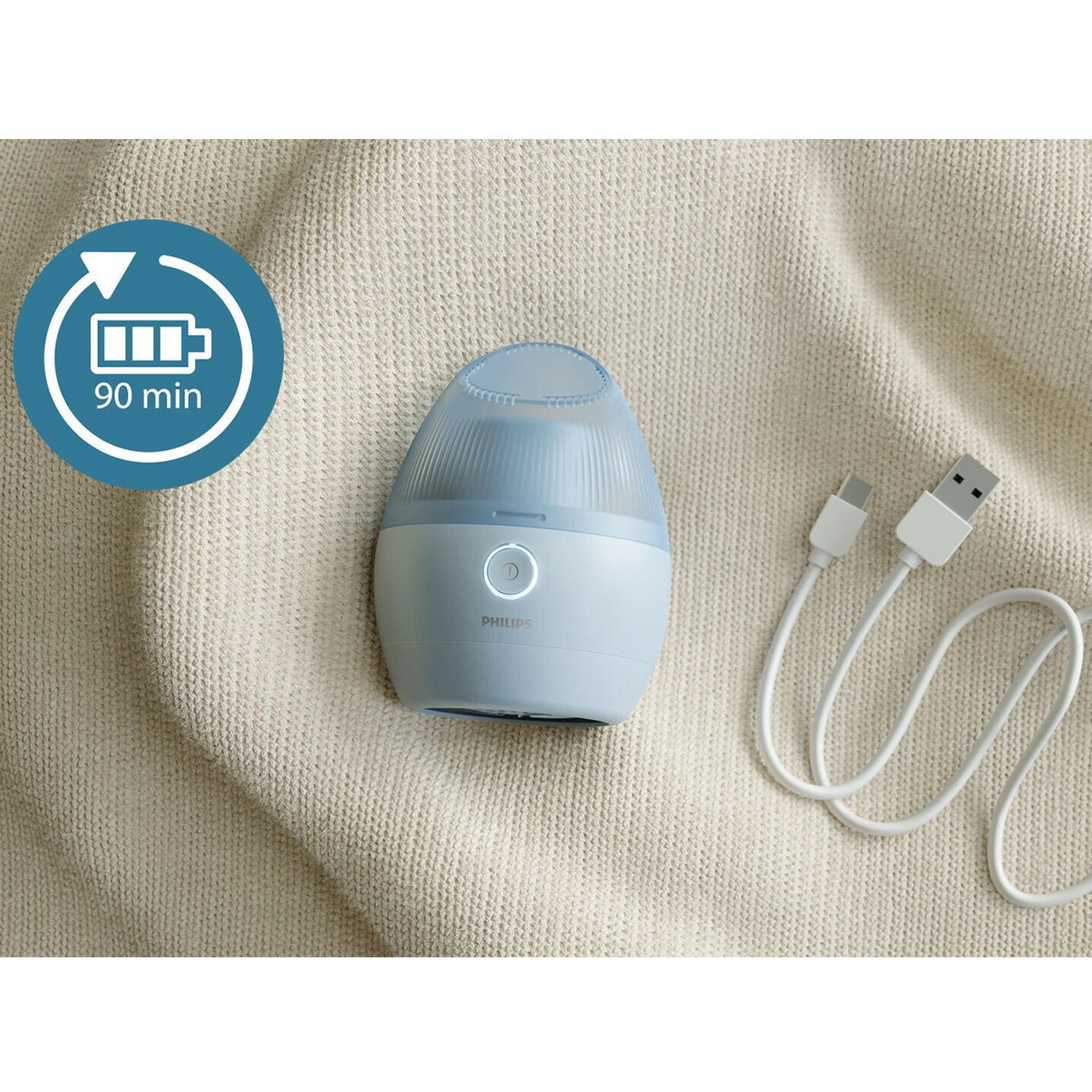 Uno sterilizzatore elettrico per biberon Philips blu e bianco su una superficie beige strutturata, con cavi.