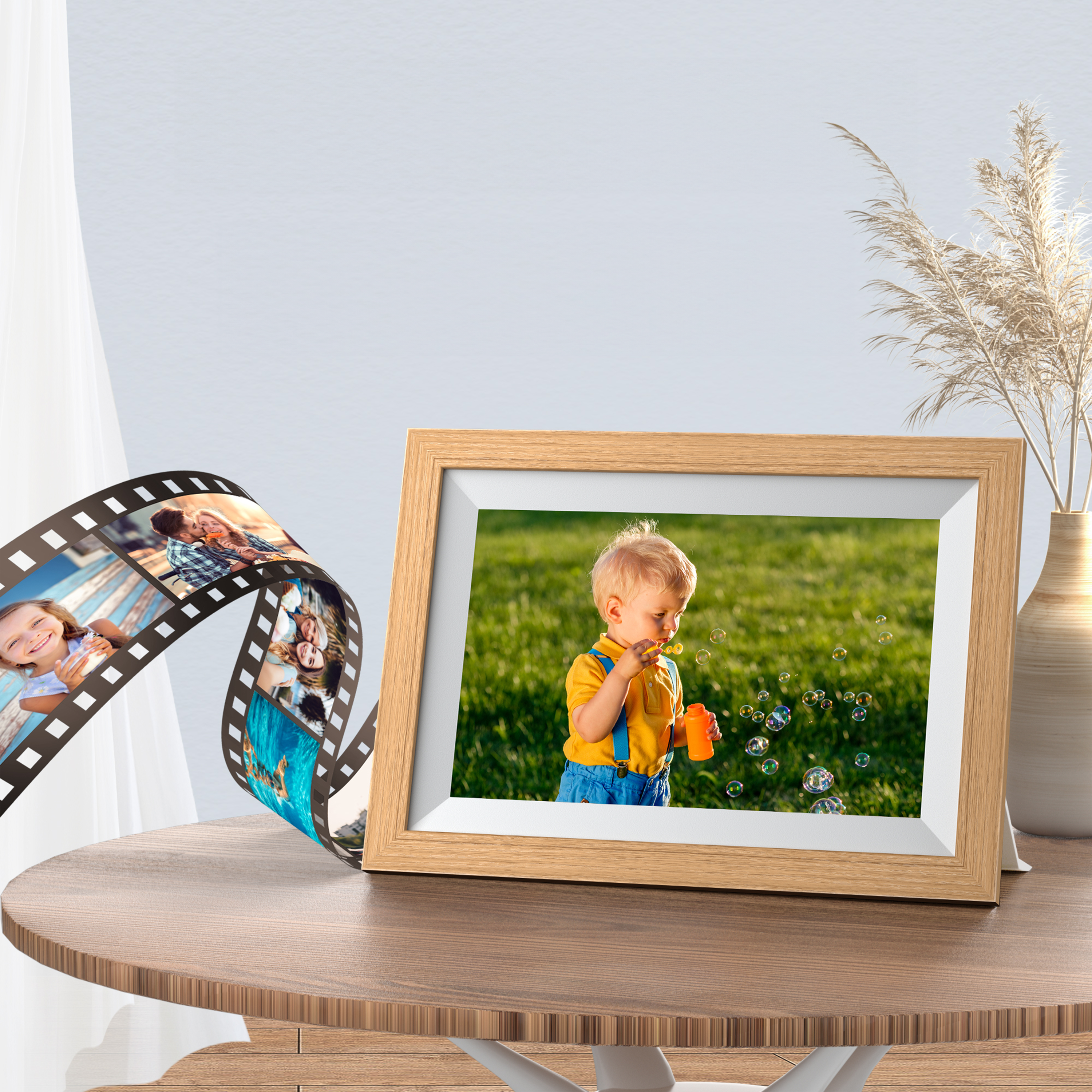 Un garçon souffle des bulles dans un cadre photo. Une bande de film est à côté du cadre sur une table.