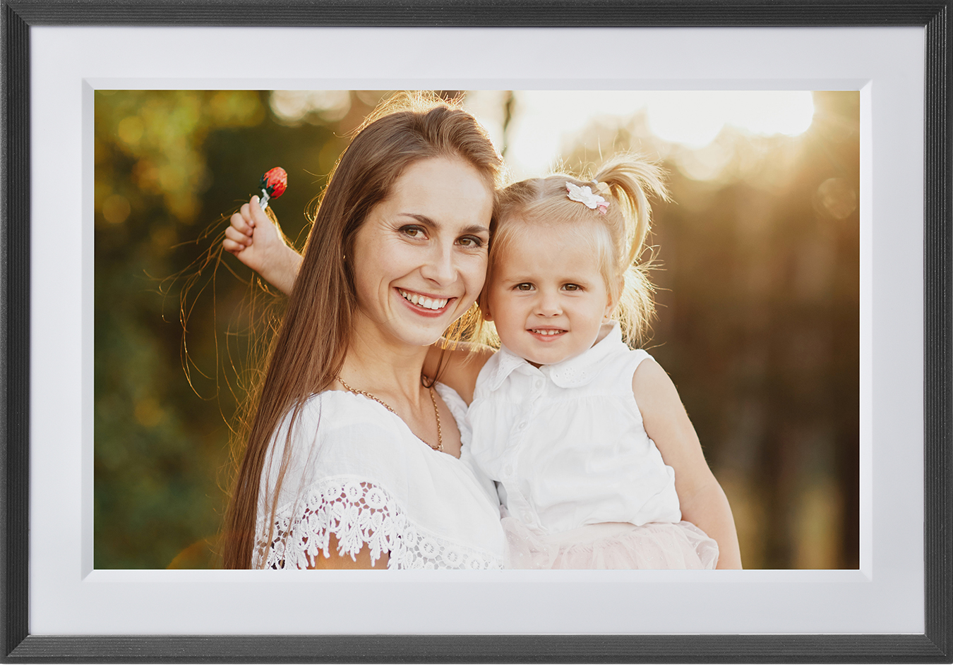 Une photo encadrée d'une femme et d'un enfant souriants. Le soleil se couche en arrière-plan.