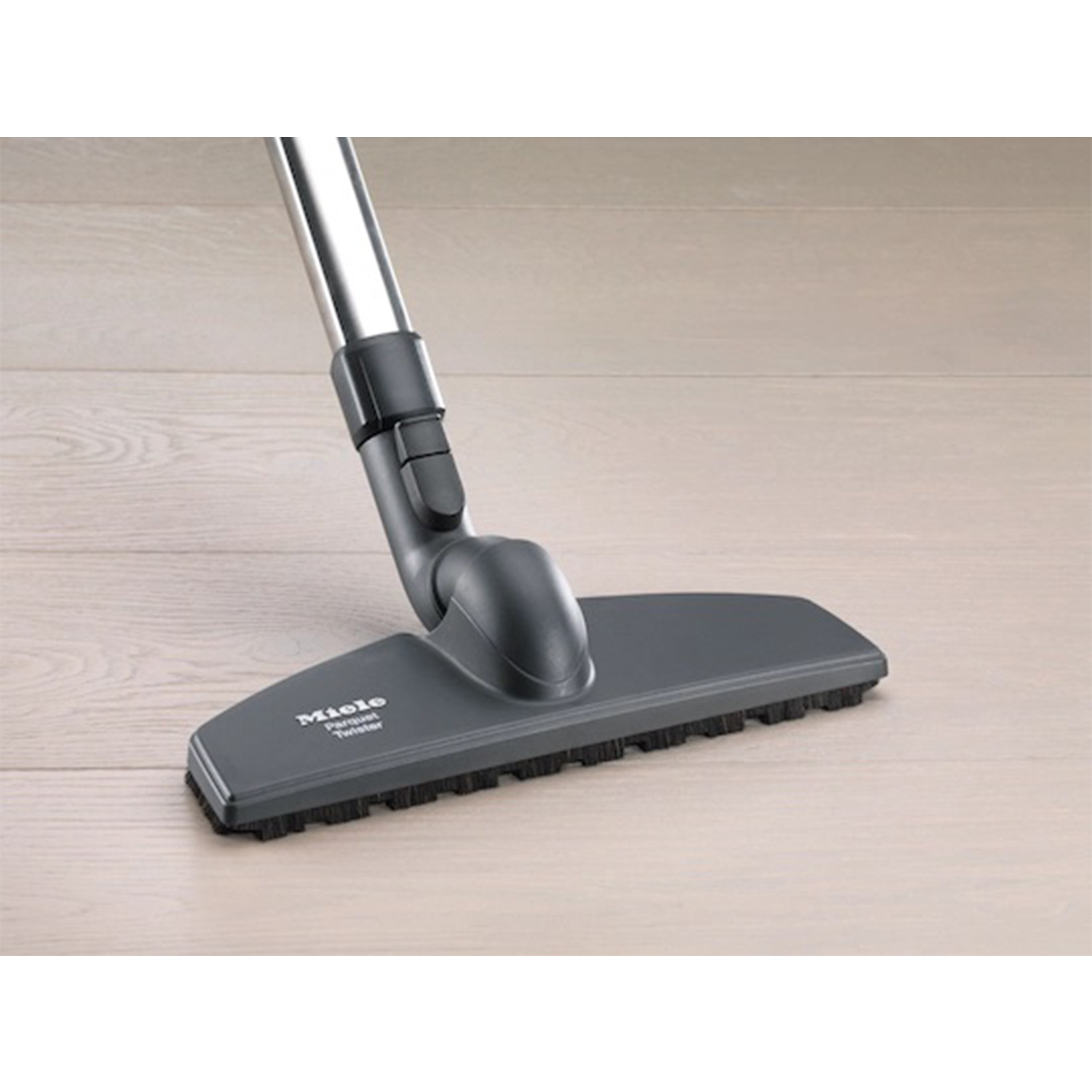 Testa dell'aspirapolvere con logo Miele su pavimento in legno chiaro.