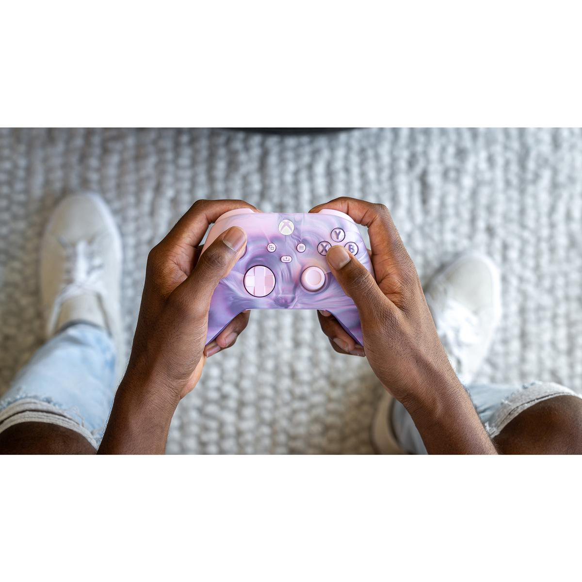 Hände halten einen lila-pinken Xbox-Controller. Weißer Hintergrund.