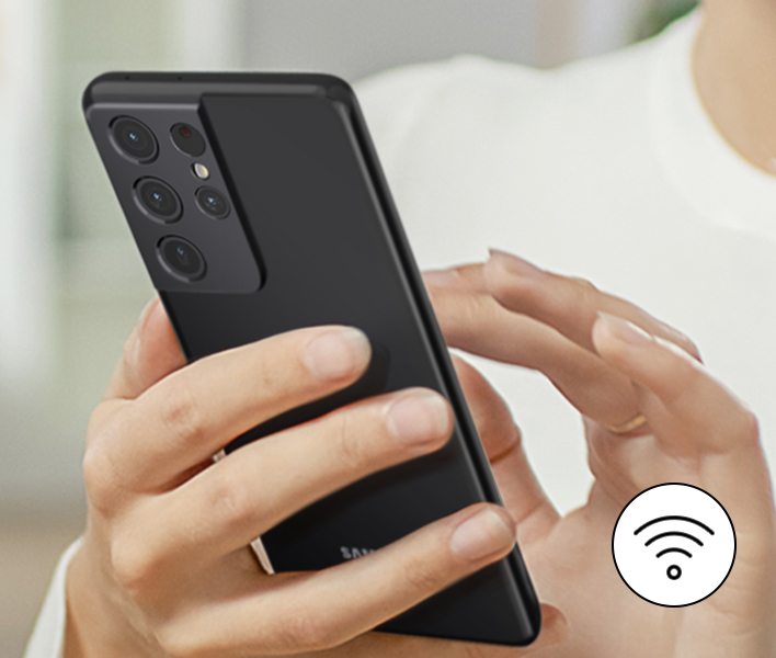 Personne tenant un téléphone noir, icône WiFi. Fond: mains et chemise de la personne.