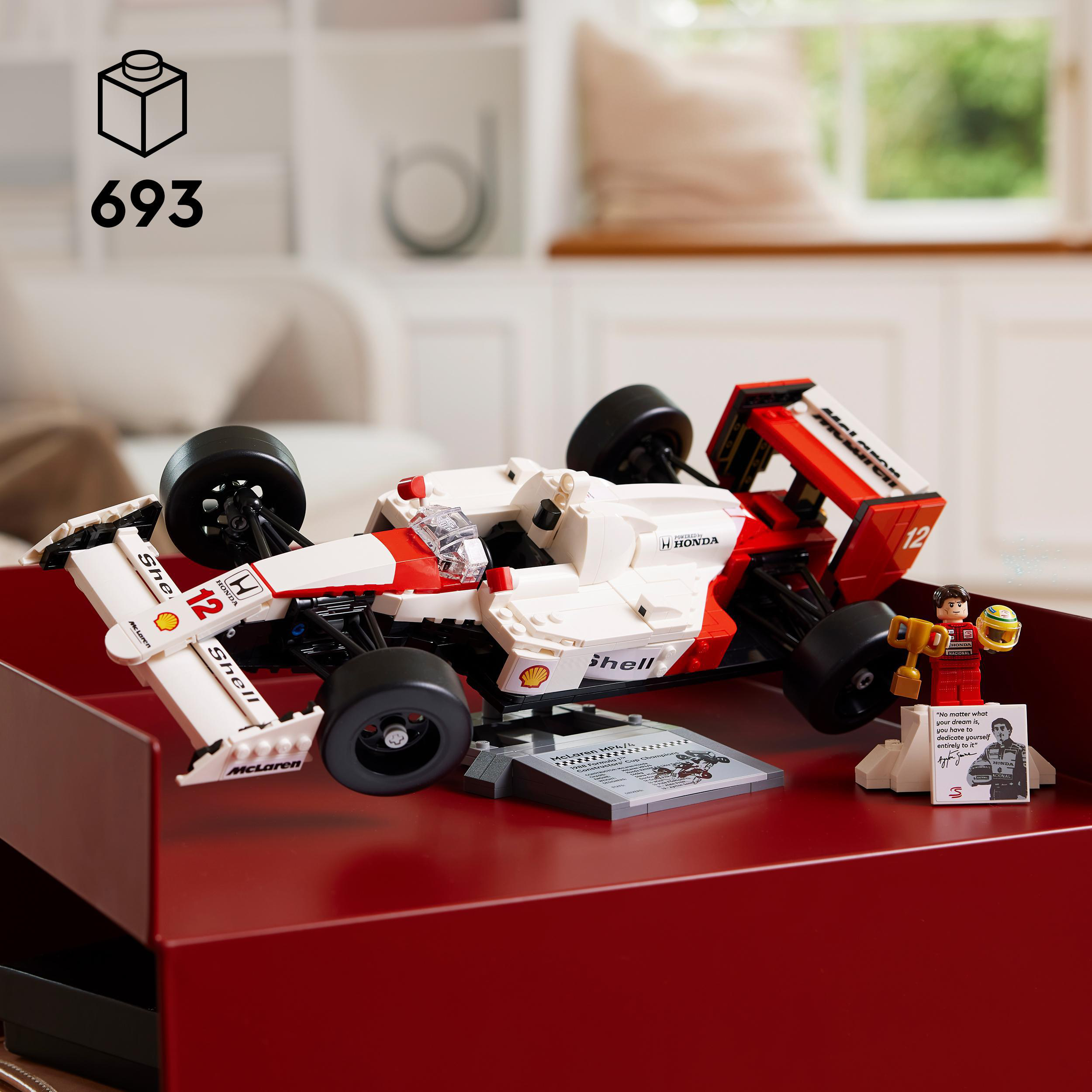 Lego-Rennwagenmodell auf rotem Tablett, mit Minifigur und Karte. Weißer Hintergrund.