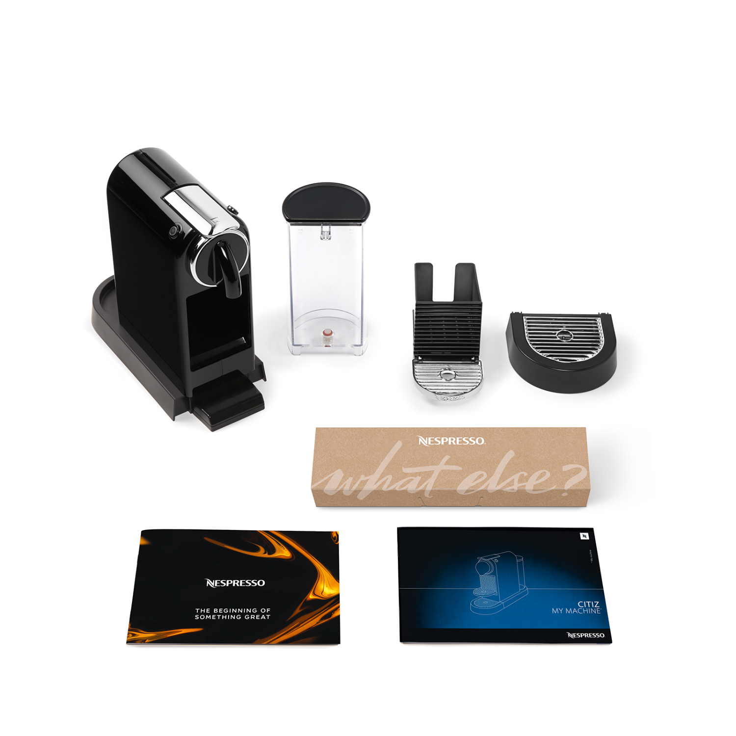 Nespresso koffiemachine en accessoires. Zwarte machine, melkopschuimer en diverse onderdelen op een wit oppervlak.