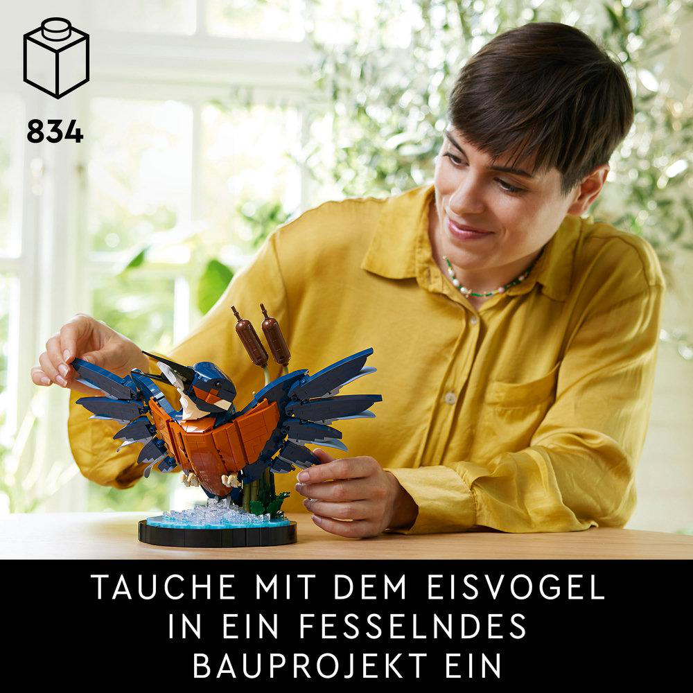 Eine Frau baut ein Lego Vogelmodell zusammen. Im Hintergrund sieht man ein Fenster mit Pflanzen und einen Tisch.