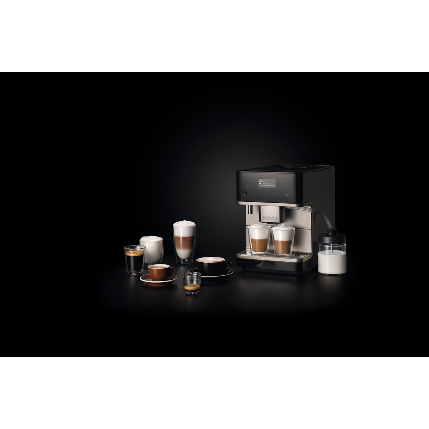 Macchina per caffè espresso con tazze e lattiera su sfondo nero.