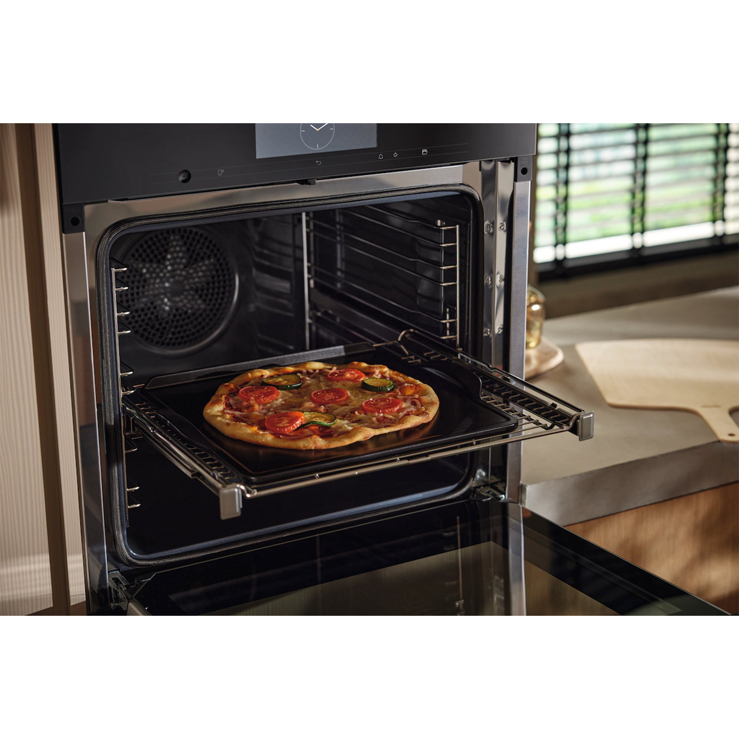 Pizza su teglia dentro il forno, porta aperta.