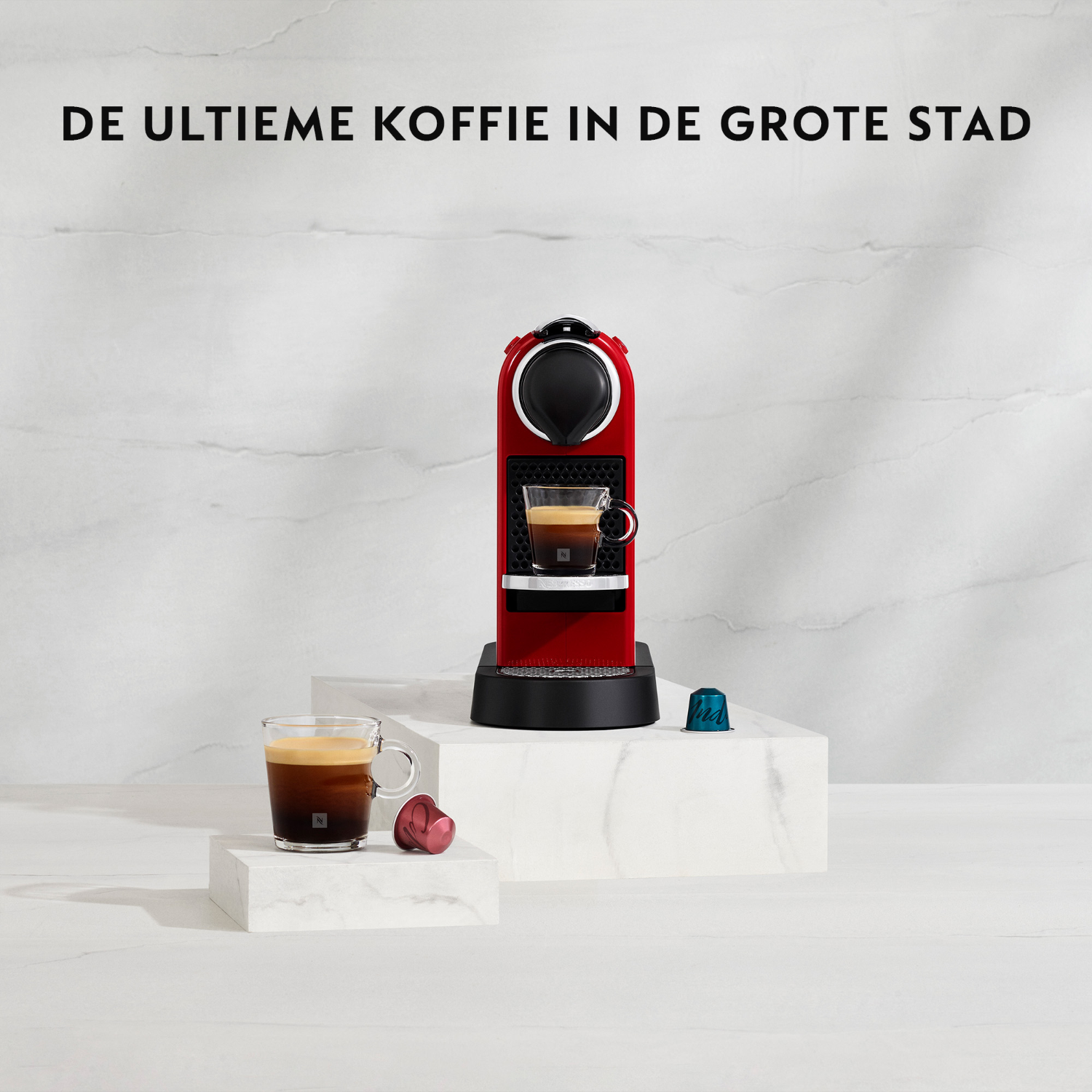 Rode Nespresso koffiemachine, met een glas koffie en capsule op witte blokken.
