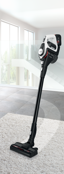 Siyah beyaz bir Bosch kablosuz elektrik süpürgesi beyaz bir halının üzerinde duruyor.