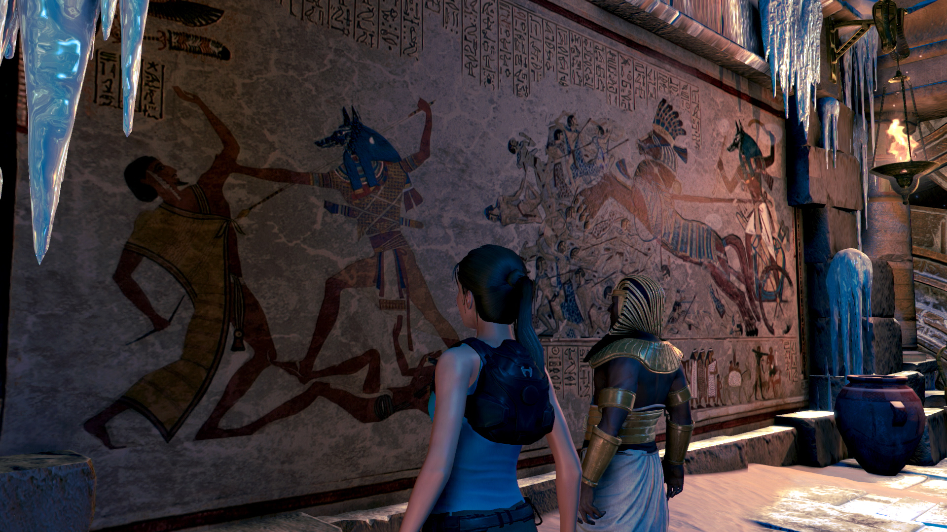 Lara Croft en een figuur in een oude, beschilderde kamer.