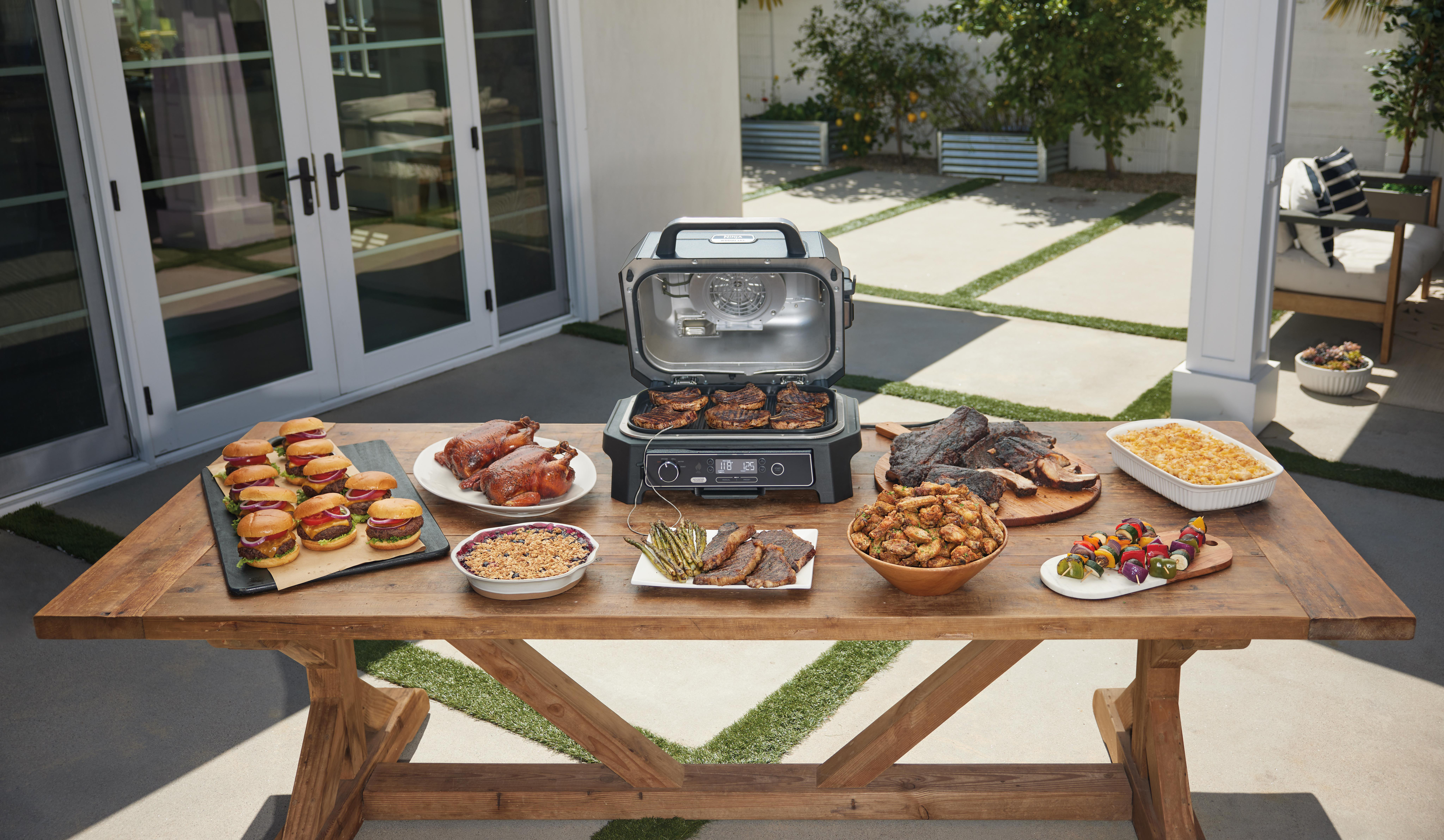 Tisch mit gegrilltem Essen. Burger, Spieße, Brathähnchen, Gemüse und mehr.
