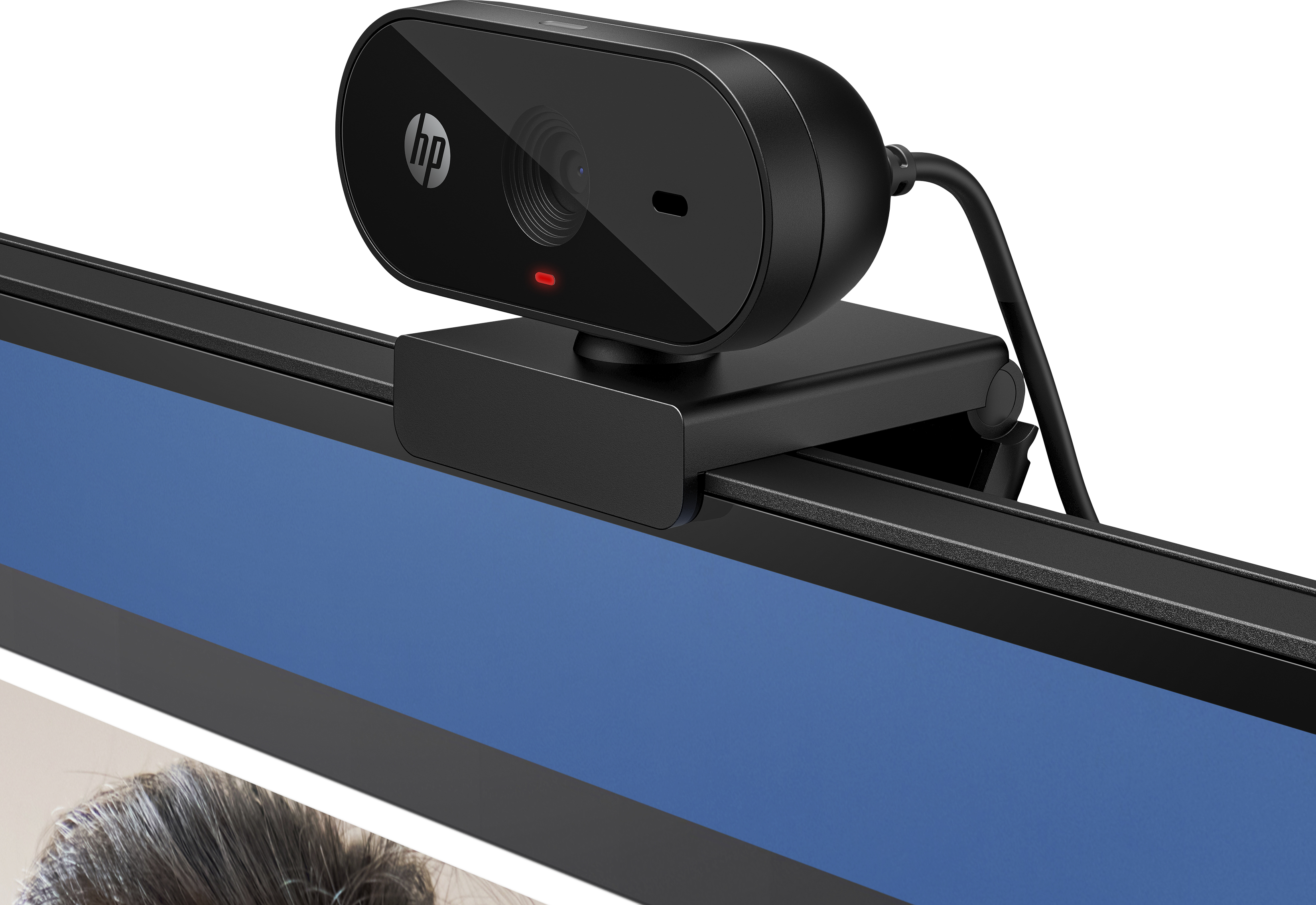 Webcam HP noire sur un moniteur. Indicateur lumineux rouge visible. Fond bleu.