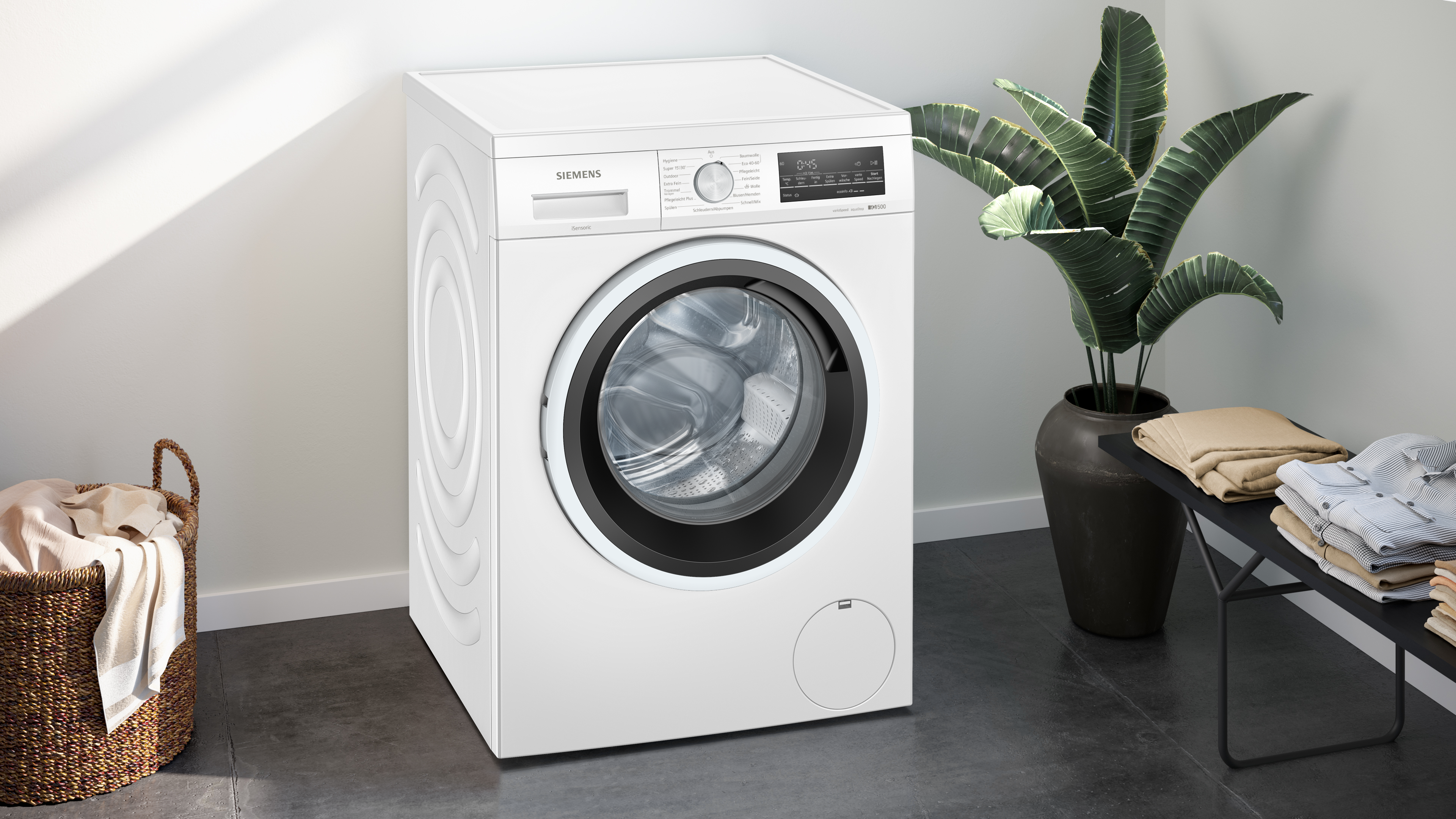 Eine weiße Siemens-Waschmaschine in einem Raum mit einer Pflanze und einem Korb.