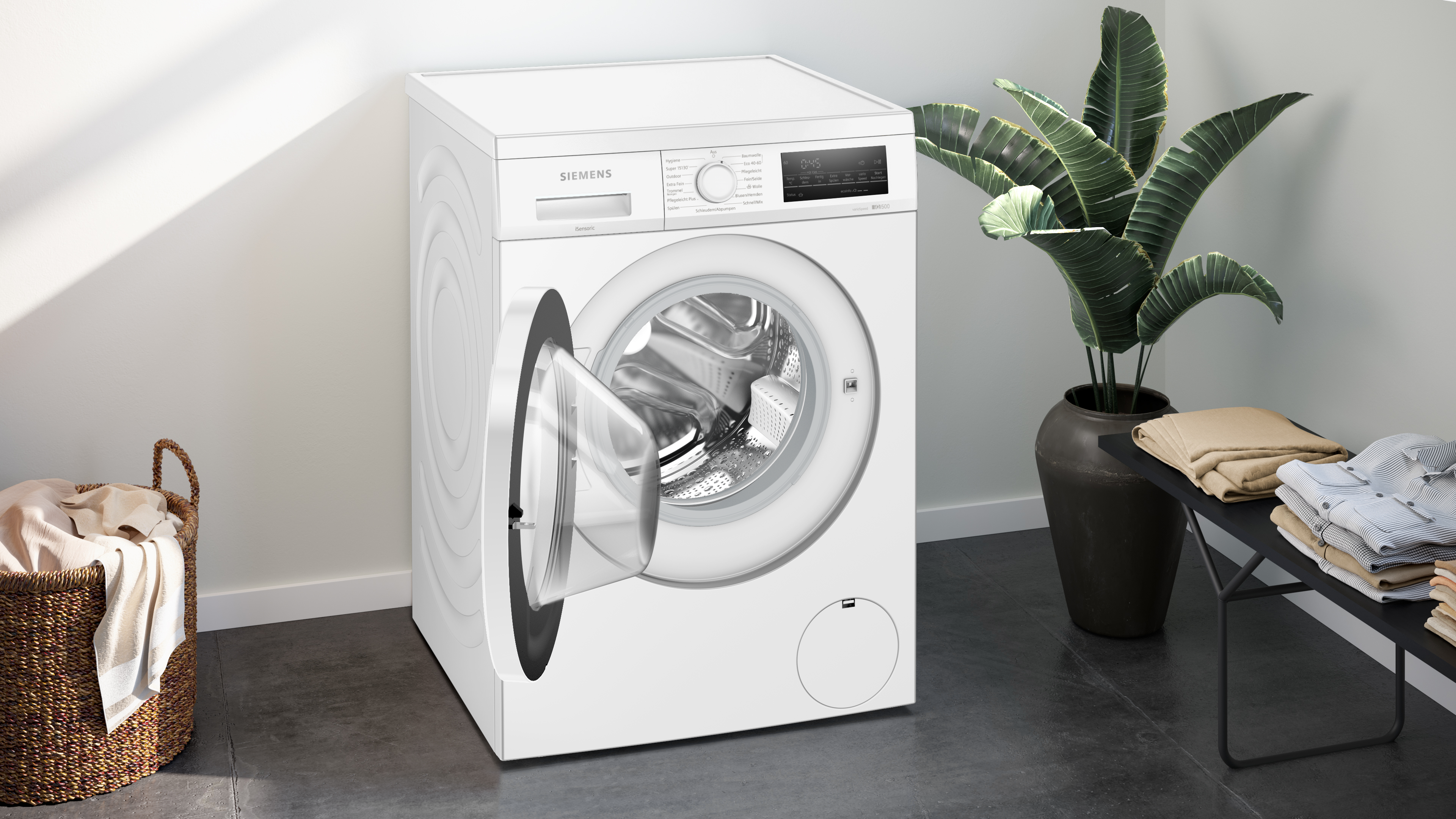 Weiße Siemens Waschmaschine mit offener Tür, Wäschekorb und Pflanze im Hintergrund.