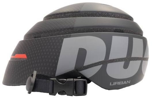 Czarny kask rowerowy z szarymi akcentami. Słowo URBAN jest widoczne. Widoczny jest pasek i klamra.