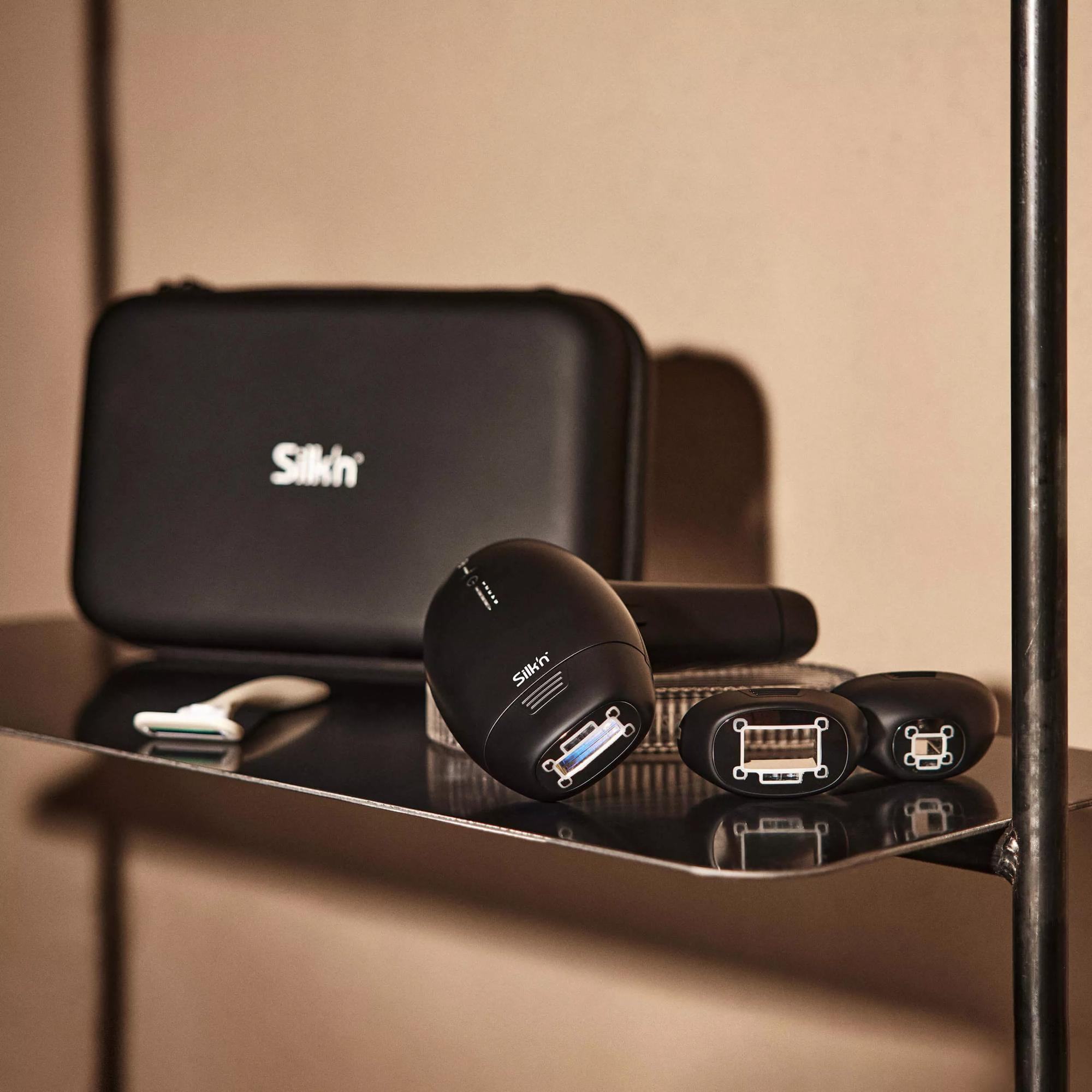 Czarny zestaw do usuwania włosów Silk'n i akcesoria ułożone na półce.