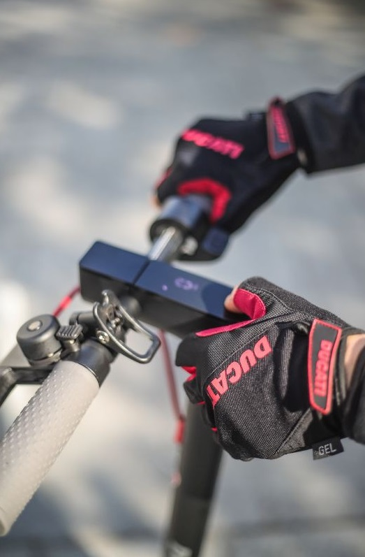 Dłonie w rękawicach regulujące elementy sterujące skutera.