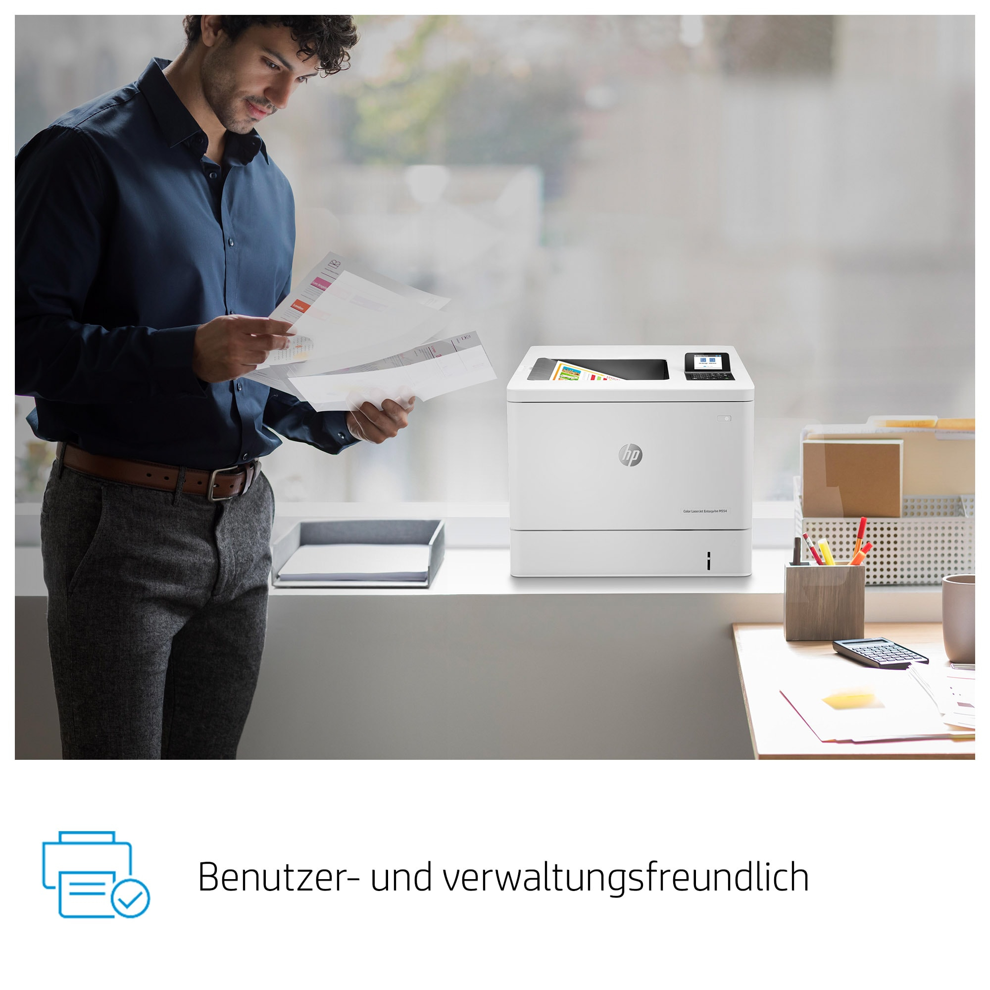 Mann in blauem Hemd betrachtet Papiere neben einem weißen Drucker. Andere Büroartikel sind sichtbar.