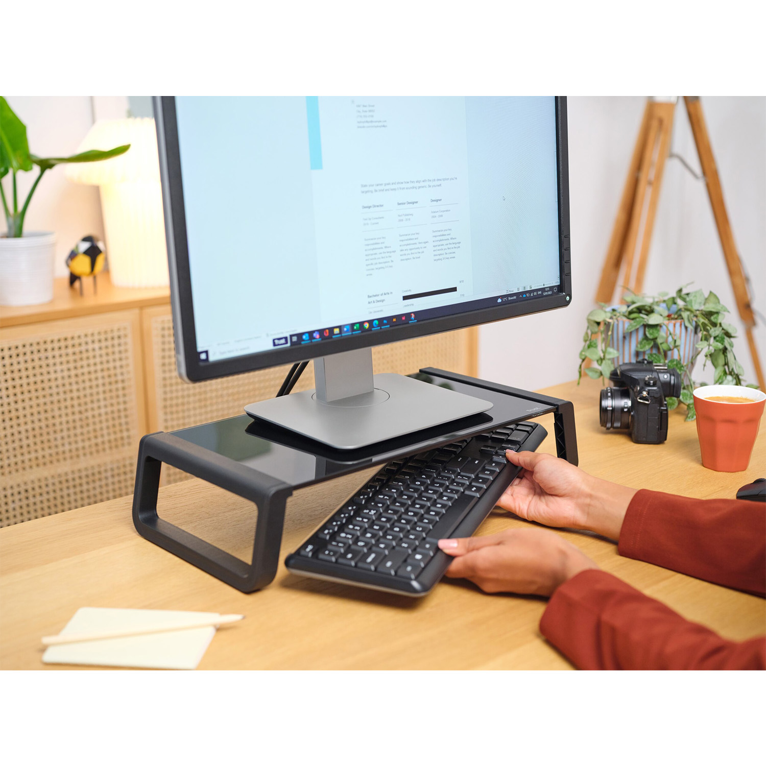 Persona che sistema la tastiera su un supporto per monitor, configurazione scrivania.
