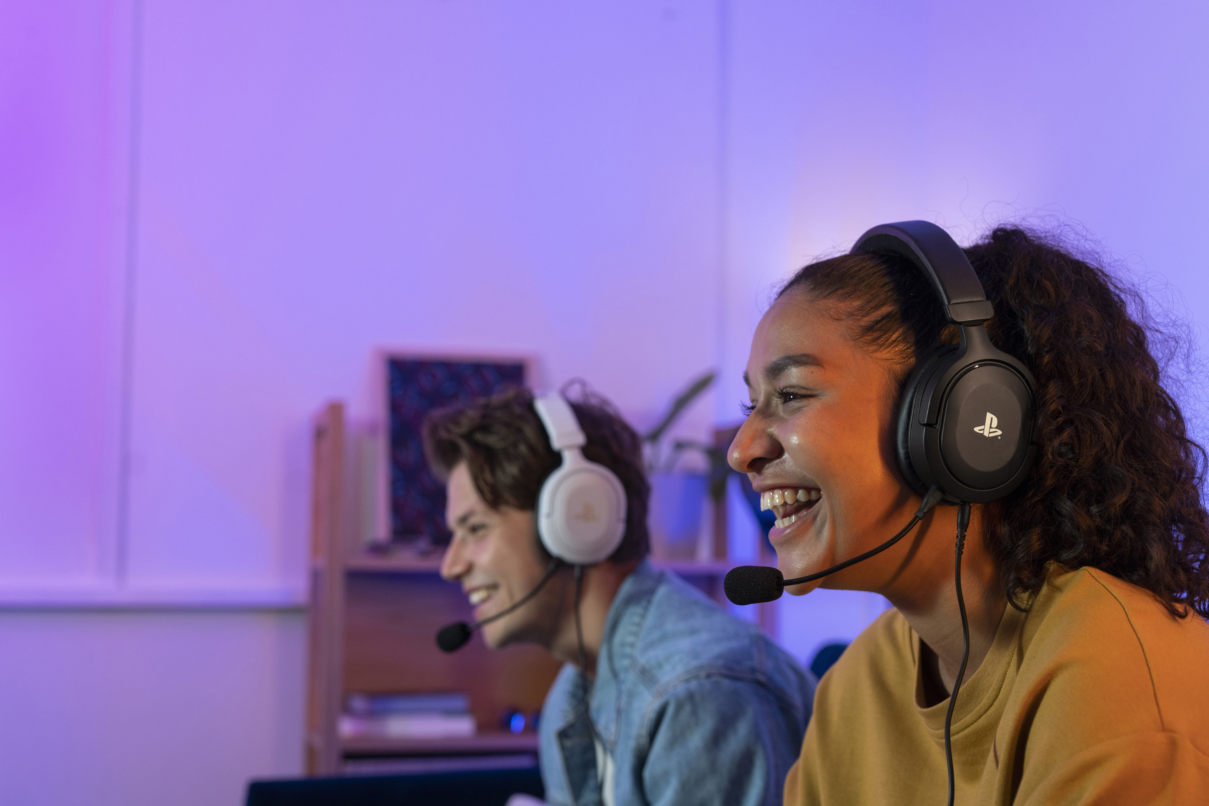 Two gamers with headsets smiling, playing a game.