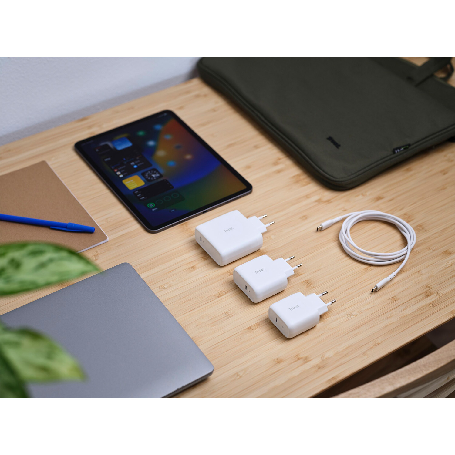 Scrivania in legno con elettronica: tablet, laptop, caricabatterie e penna. Tutto ben organizzato.